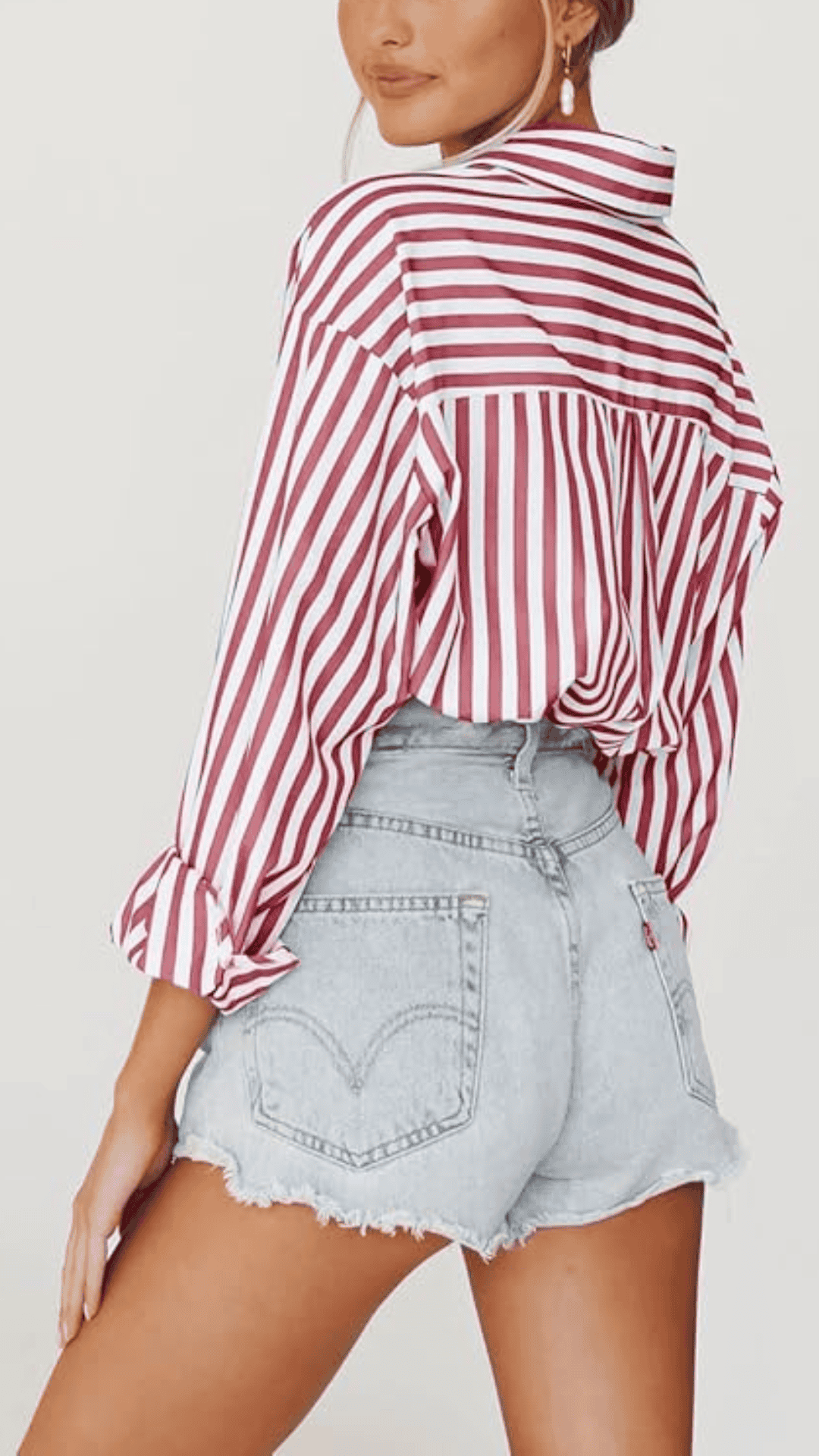 This outfit features a relaxed, button-up top with bold red and white vertical stripes paired with distressed, light-wash denim shorts, creating a classic yet playful aesthetic suitable for a casual Fourth of July celebration. The lightweight fabric offers breathability, while the overall vibe balances a fun, summery spirit with modern elegance, making it ideal for outdoor gatherings or picnics.