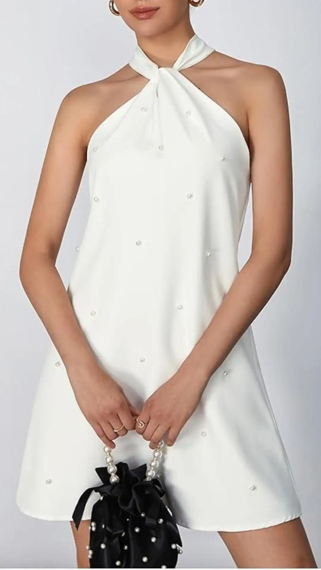 This halter-style white homecoming dress features a smooth, satin-like fabric adorned with delicate pearl embellishments, offering a touch of elegance. The relaxed fit and slightly flared hem create a playful, youthful vibe, making it ideal for a formal event or party for teenage girls.