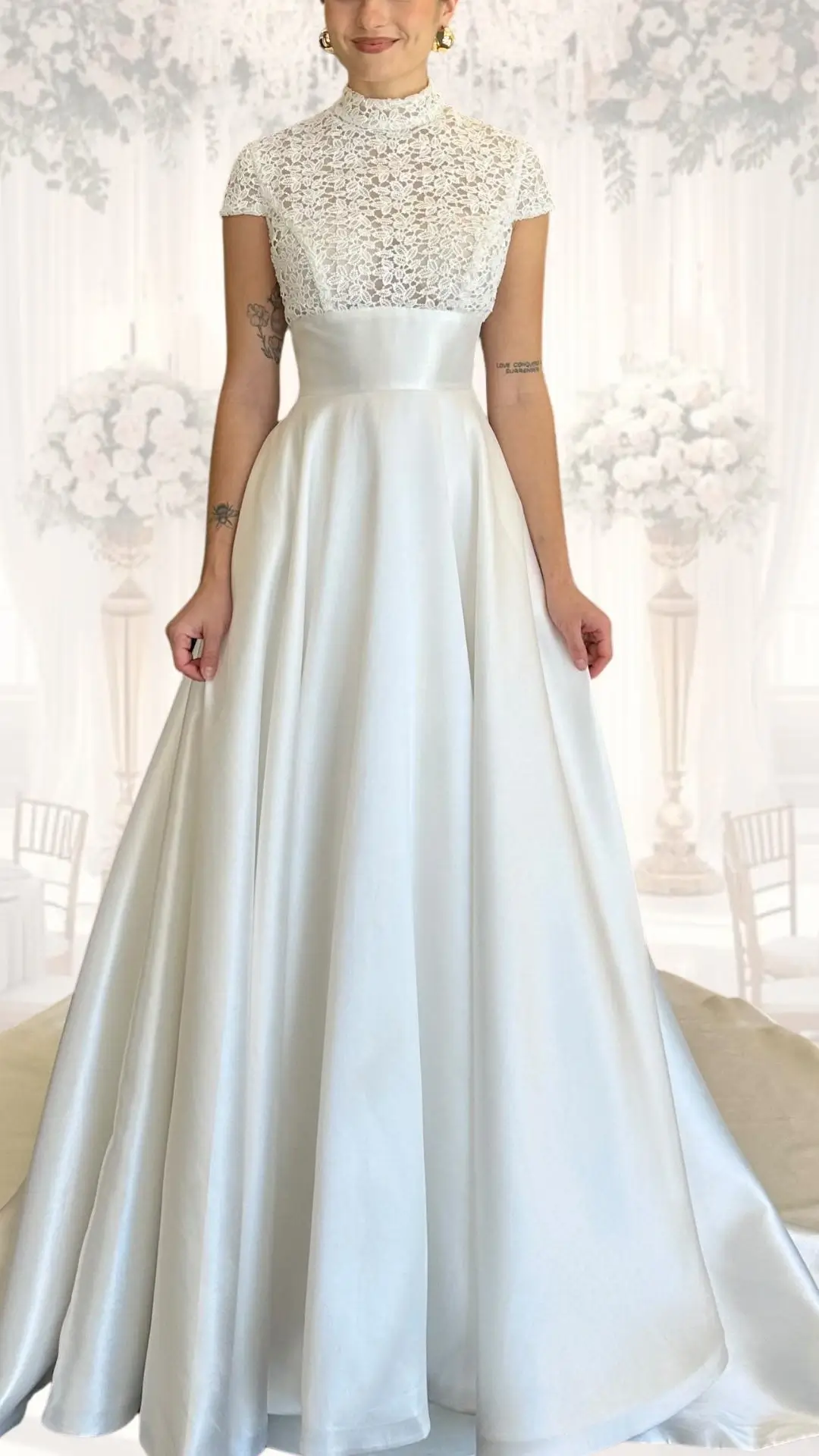 This high neck wedding gown features a delicate lace bodice with a mock neckline, complemented by short sleeves, creating a classy and modest look. The flowing skirt, made from a luxurious satin fabric in a soft ivory shade, drapes elegantly to the floor, perfect for a winter or vintage wedding style. The seamless blend of textures lends sophistication while ensuring comfort and warmth.
