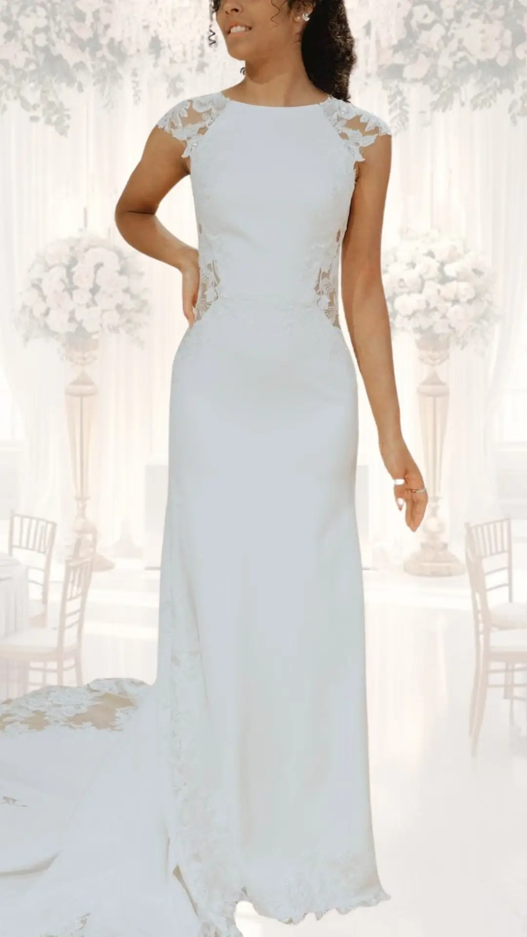 This high neck wedding gown features a fitted silhouette made from smooth satin, accented by delicate lace cap sleeves and intricate lace side panels. The gown is a soft, classic white, creating an elegant and modest look, perfect for a winter or vintage wedding. A subtle train at the back adds a sophisticated touch, enhancing the overall timeless appeal of the dress.
