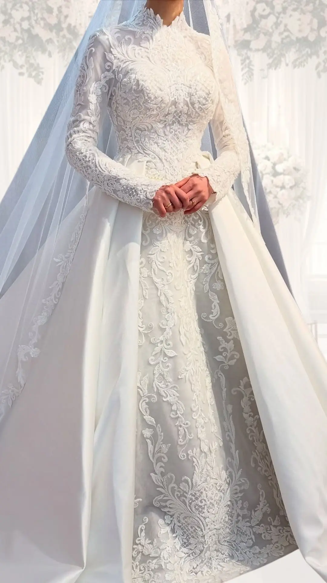 This high neck wedding gown features intricate lace detailing and delicate embroidery on a soft white fabric, complemented by long, fitted sleeves. The elegant design includes a luxurious full skirt with a flowing train, making it ideal for a winter wedding with a classy, modest aesthetic. The gown exudes vintage charm, enhanced by its structured bodice and tailored silhouette.