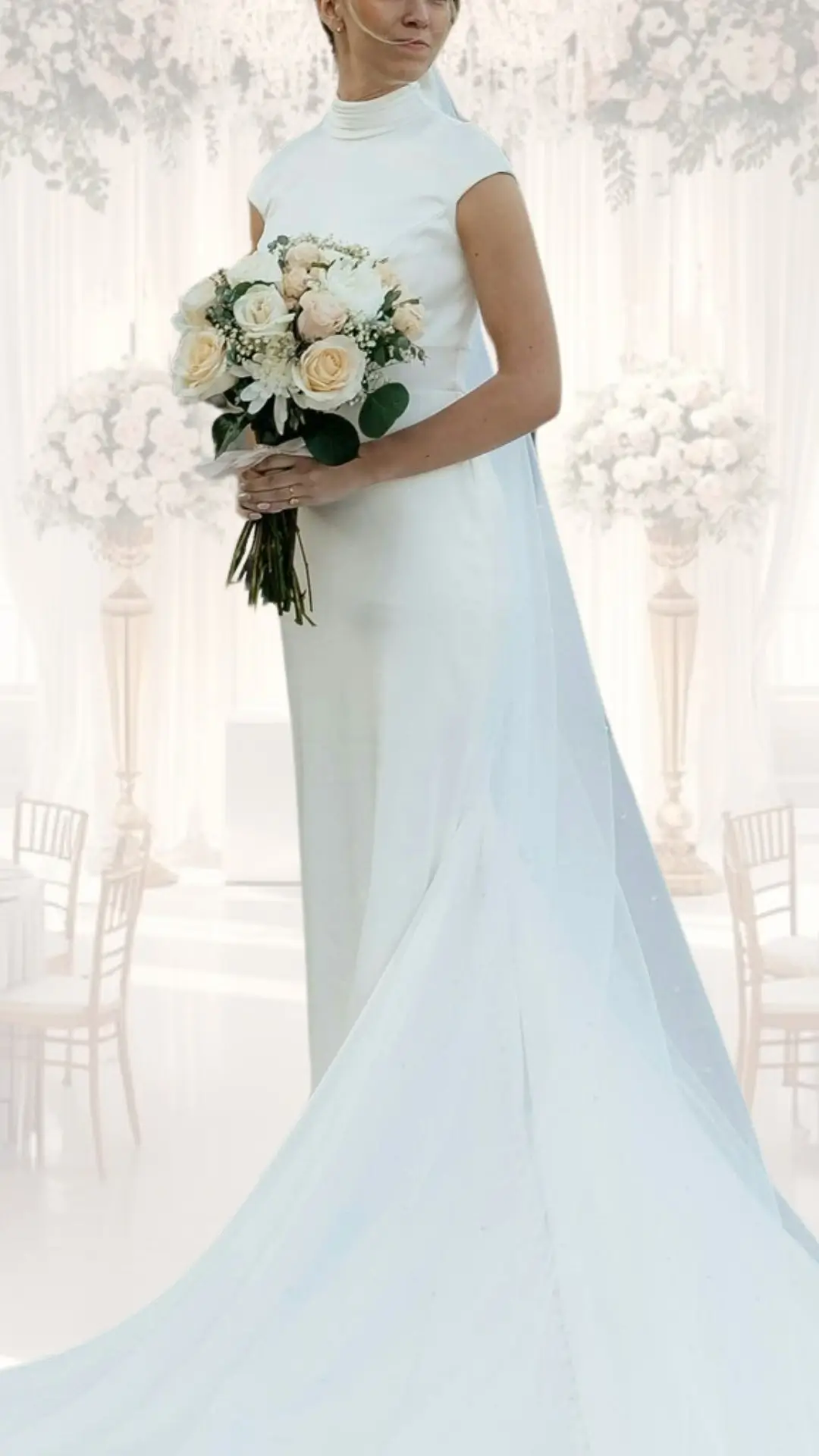 The wedding gown features a high neck design and a form-fitting silhouette, crafted from a smooth, lightweight fabric in a soft white shade. It has short sleeves and a delicate train, offering a vintage yet modern look, perfectly suited for a winter wedding. The bride holds a bouquet of soft pastel roses, complementing the gown's elegant aesthetic.