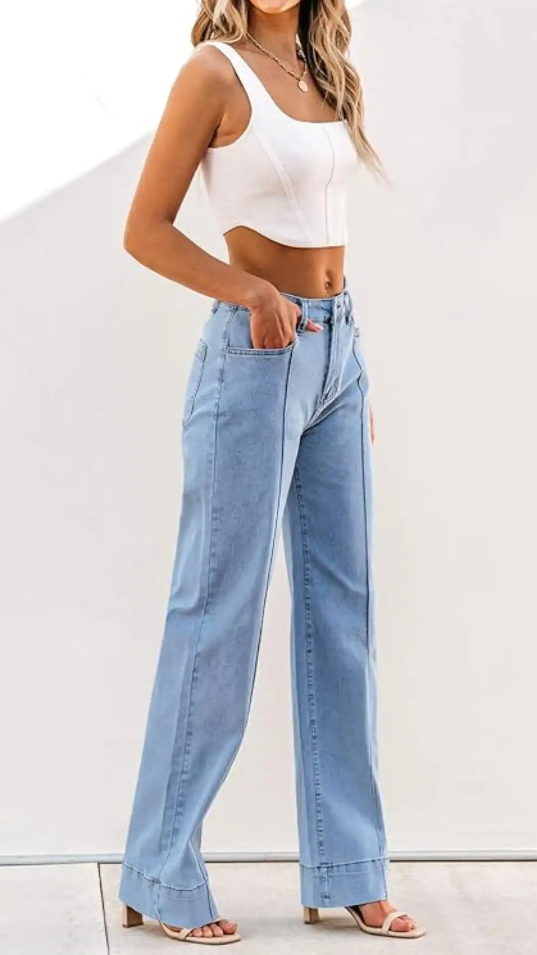High-waisted light blue denim jeans feature a relaxed, wide-leg silhouette that falls to the ankles, accentuating a casual yet chic vibe. The fabric is soft denim with a matte texture, complemented by a clean design that includes side pockets and is styled for a laid-back outing or everyday wear.