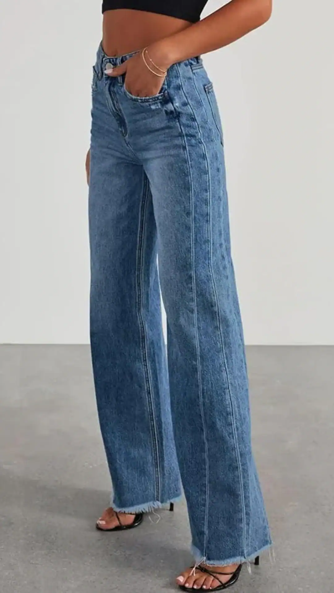 High-waisted, wide-leg jeans in a medium blue denim, featuring a classic silhouette with a frayed hem for a relaxed edge. The fabric offers a sturdy texture, making these jeans suitable for casual outings or paired with dressier tops for a night out.