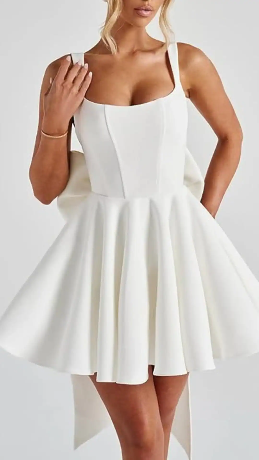 This white homecoming dress features a structured, fitted bodice with a square neckline and thick straps, leading into a playful, voluminous skirt made from a smooth, textured fabric. Its overall vibe is trendy and youthful, making it an ideal choice for a school dance or homecoming event.