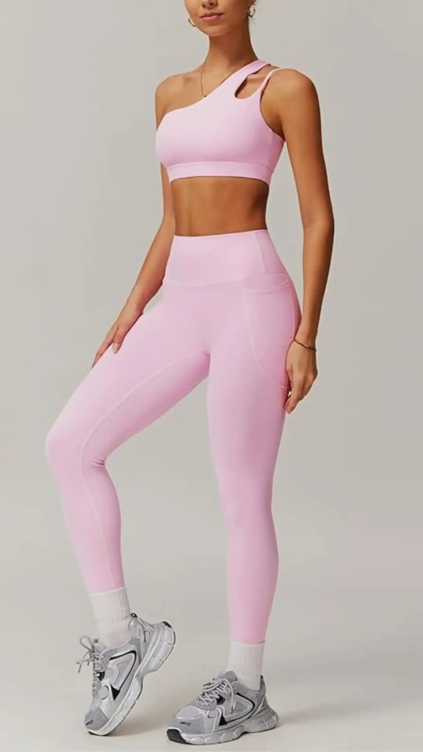 This two-piece outfit features a soft, stretchy blend of 78% polyamide and 22% elastane, crafted in a light pink color that exudes a youthful and elegant vibe. The single-shoulder, backless sports bra and high-waisted leggings designed for comfort and support are perfect for active occasions, emphasizing a slim silhouette with stylish cut-outs and seamless construction.