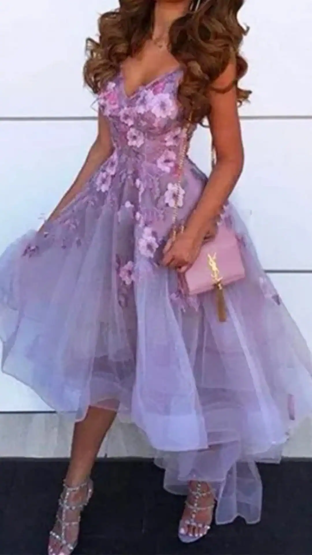 This enchanting homecoming dress features a fitted bodice adorned with delicate floral appliqués in soft shades of lilac, transitioning into a voluminous, sheer tulle skirt that sways gracefully with movement. The overall vibe is romantic and ethereal, perfect for a formal teen occasion like homecoming, while the lightweight fabric and intricate design details create a dreamy, eye-catching silhouette.