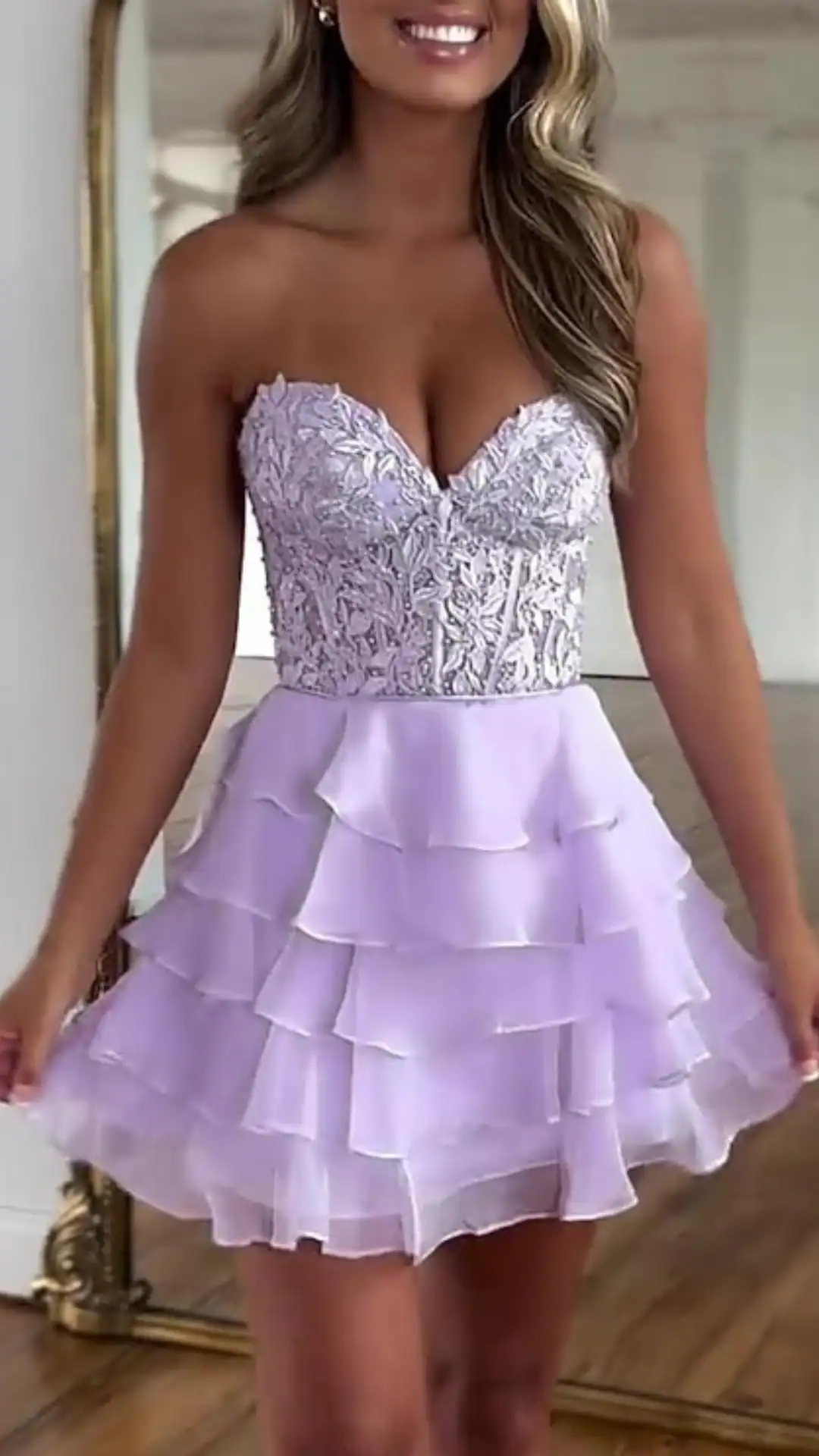 This stunning homecoming dress features a lilac color with intricate silver embroidery on a fitted bodice, leading to a flared, layered skirt made of lightweight chiffon. The combination of a structured sweetheart neckline and cascading ruffles provides a youthful, playful vibe, perfect for a fun and elegant teenage event.