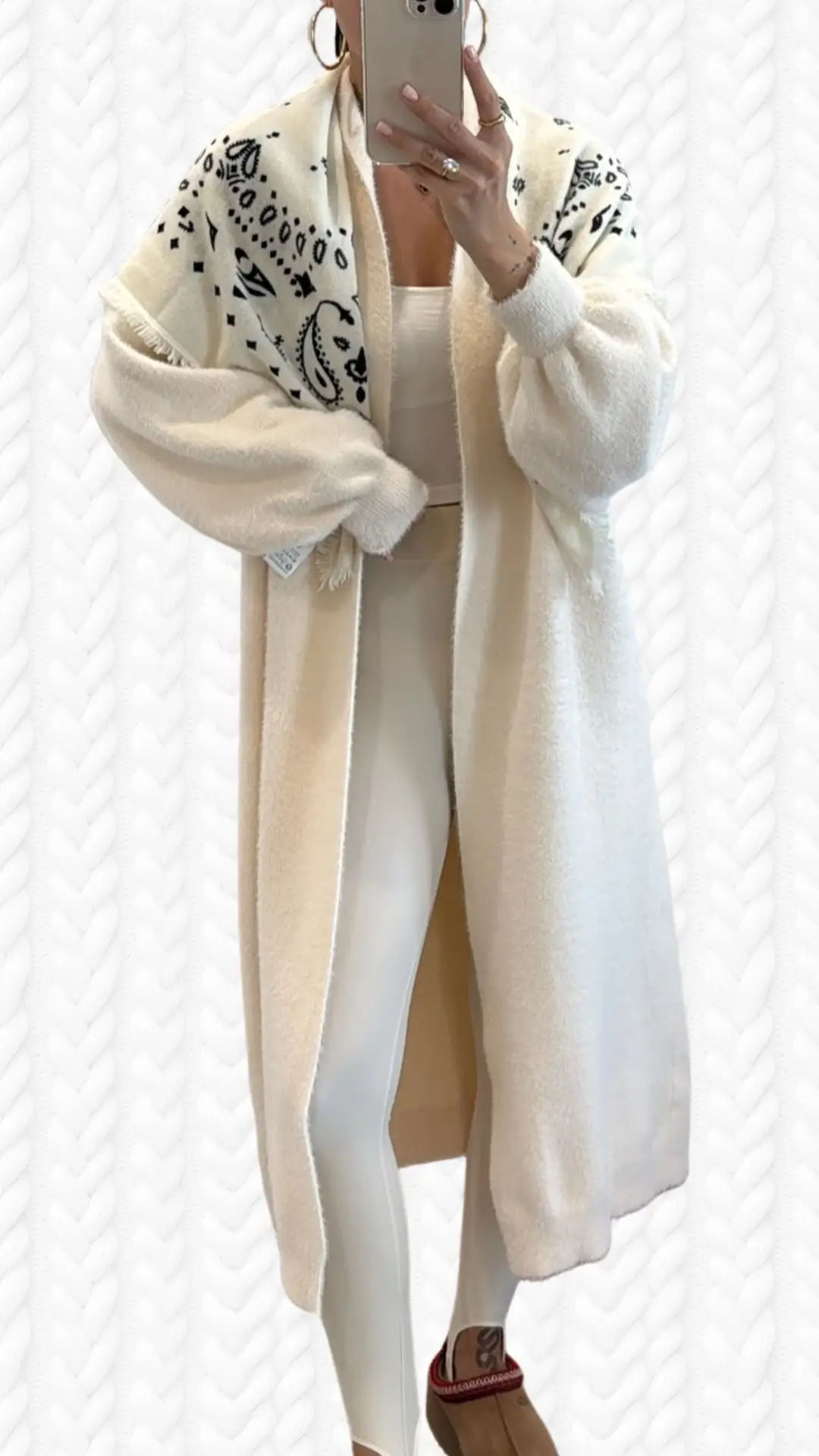 This outfit features a soft, cream-colored long cardigan with a textured, patterned shawl collar in black and white accents, adding depth and style. The cardigan has voluminous sleeves and falls open, revealing a form-fitting, light beige bodysuit paired with sleek, white leggings and brown platform mules. The overall look combines comfort and elegance, perfect for a chic casual ensemble.