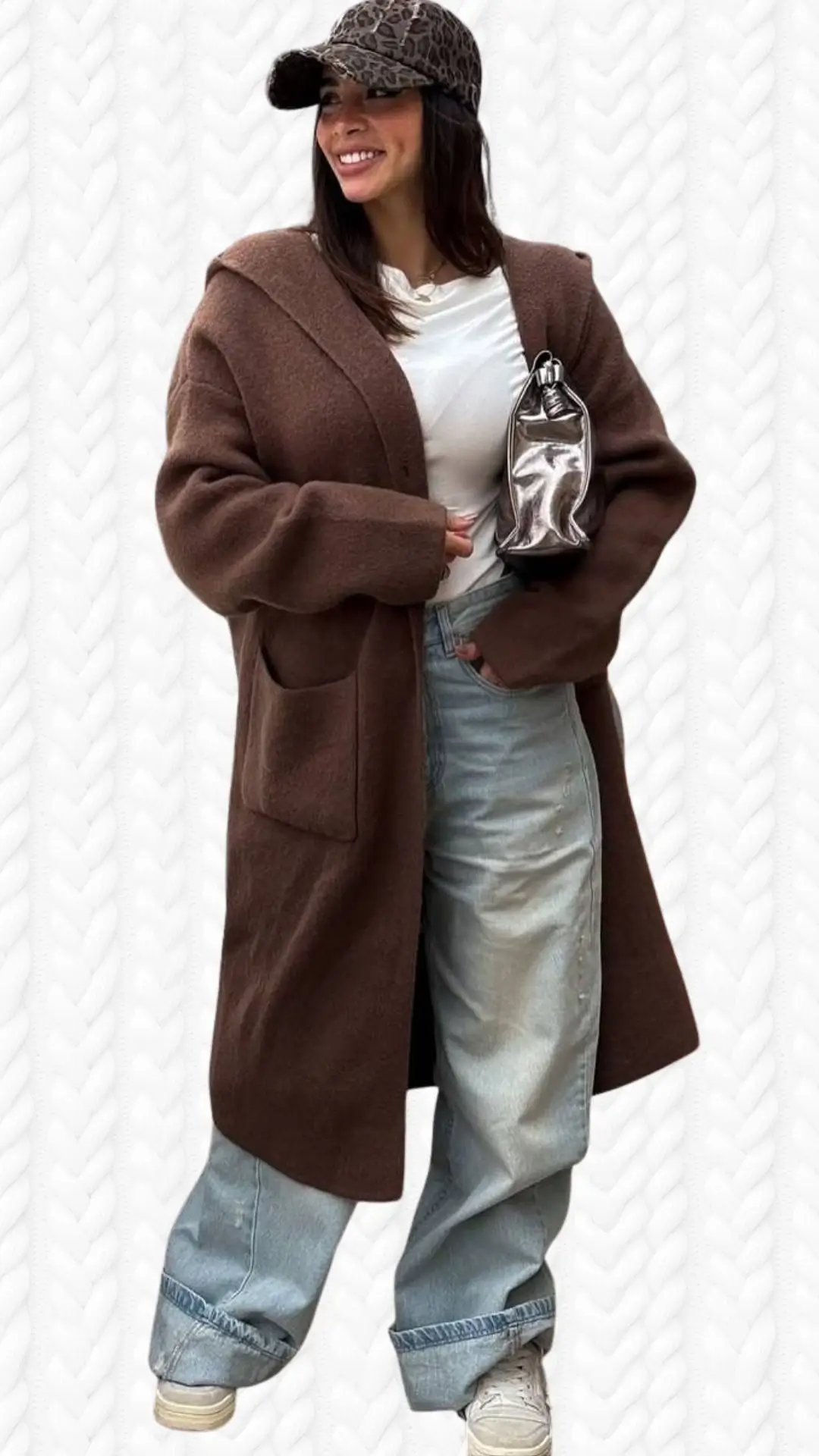 A cozy brown long cardigan made of soft fabric features an oversized silhouette, wide sleeves, and two front pockets, paired with a white crew-neck t-shirt. The outfit includes light blue, relaxed-fit jeans that are cuffed at the hem and white sneakers, complemented by a stylish leopard-print cap. The overall look combines comfort and casual elegance, making it a versatile choice for various occasions.