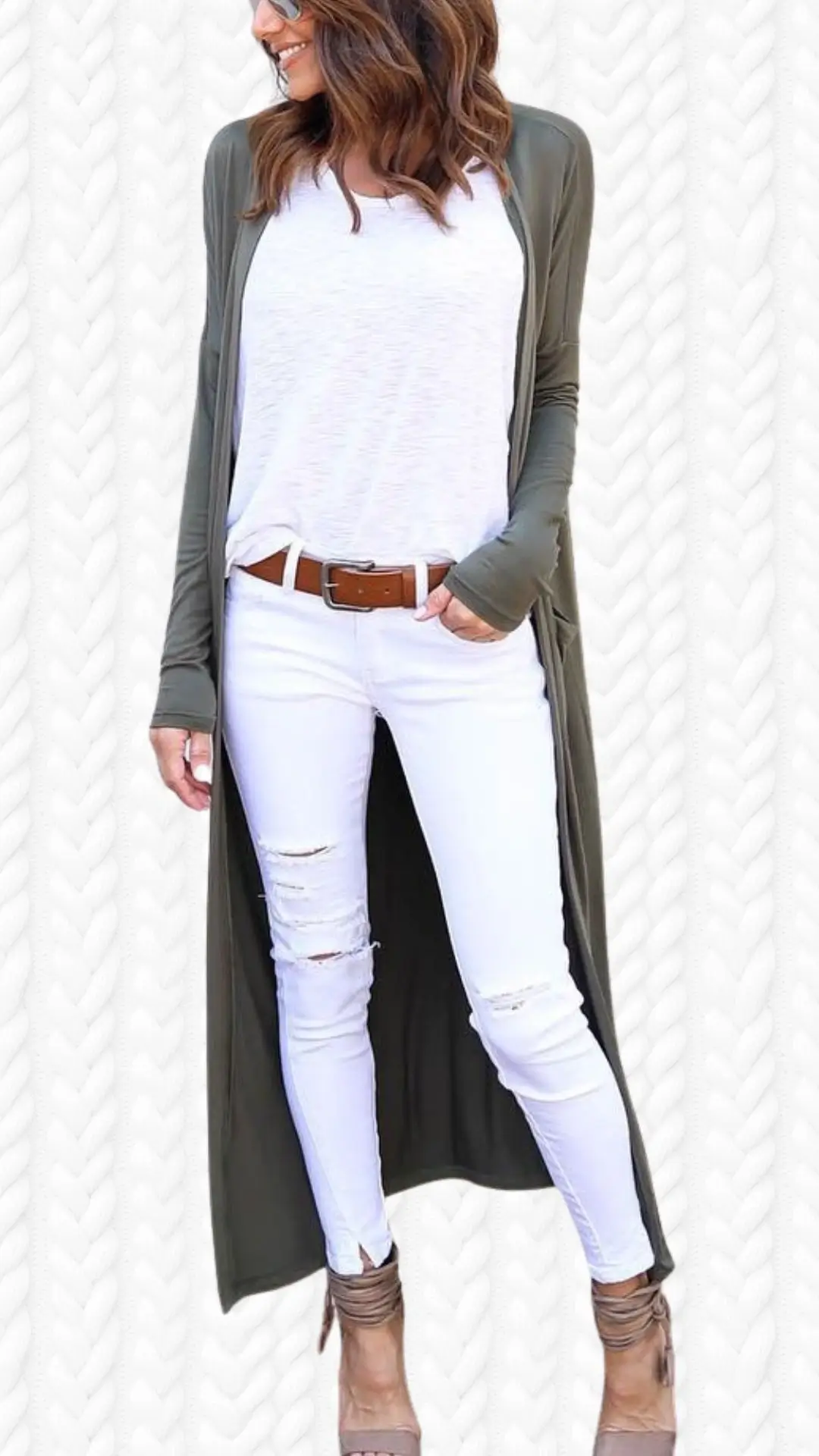 A long olive green cardigan made from soft, lightweight fabric drapes casually over a white, relaxed-fit T-shirt. It features long sleeves and an open front, paired with distressed white skinny jeans and taupe ankle strap heels, creating a stylish and effortless look. The ensemble is completed with a brown belt that adds a touch of contrast, exuding both comfort and fashion.