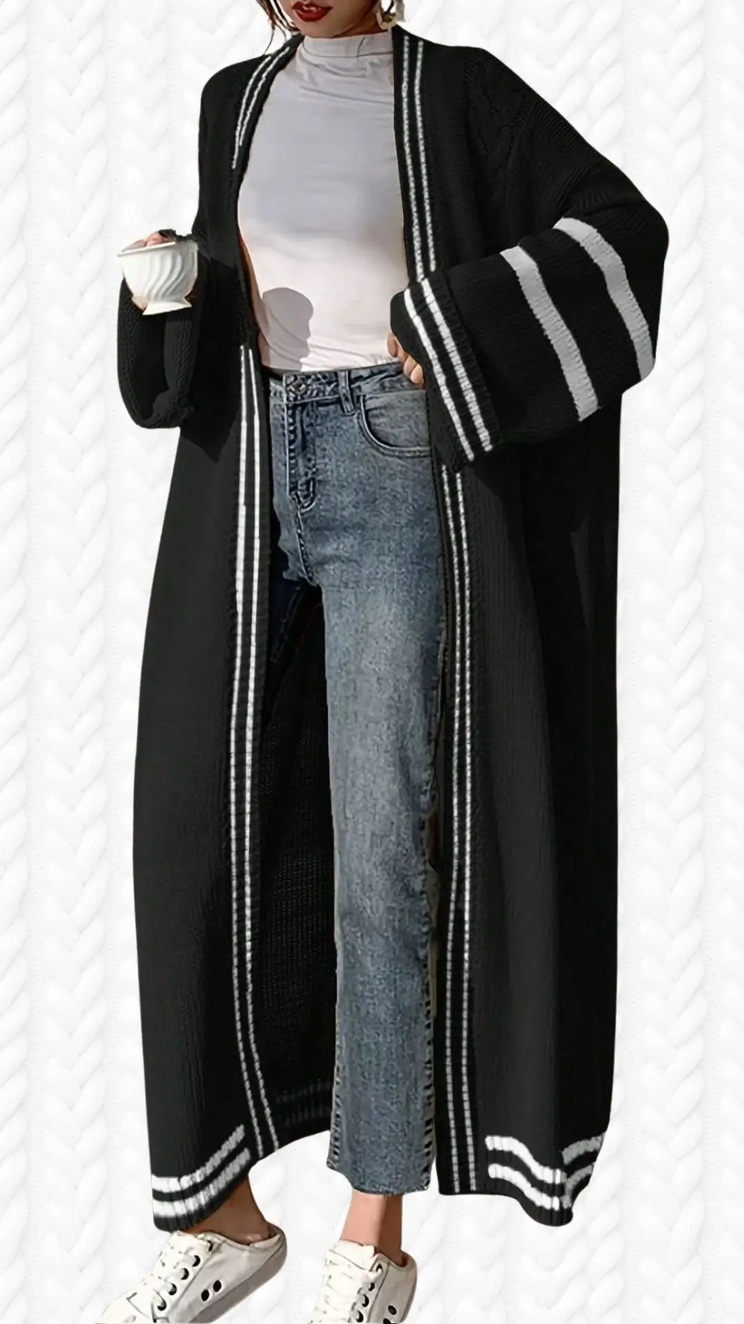 The outfit features a long black cardigan with a ribbed texture and white striped detailing along the edges and sleeves, offering a chic contrast. It is styled over a fitted white mock neck top and paired with high-waisted, light-wash denim jeans. The look is completed with white lace-up sneakers, creating a stylish and relaxed ensemble.