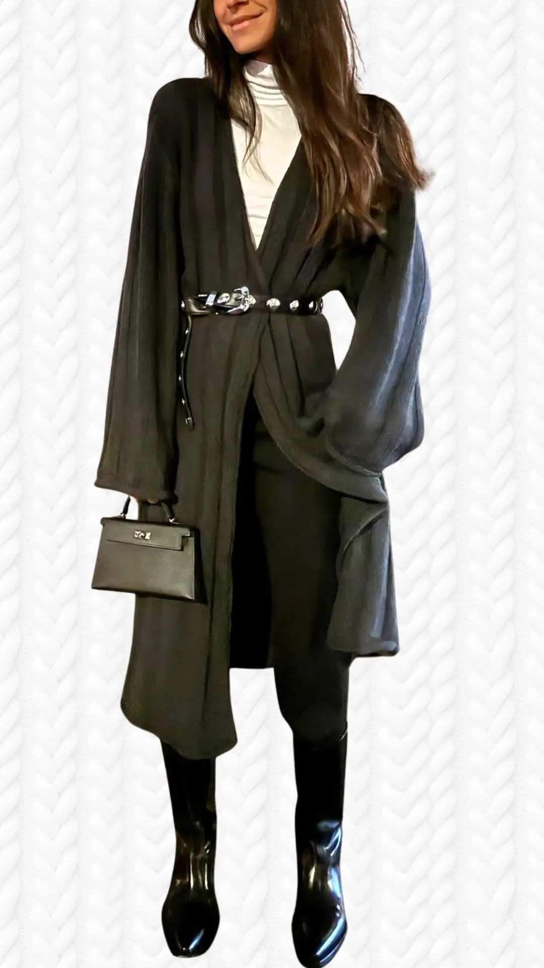 A flowing black long cardigan made from lightweight, textured fabric features billowy sleeves and a deep V-neckline, cinched at the waist with a shiny black belt embellished with metallic accents. The outfit is paired with sleek black knee-high boots and a structured black handbag, creating a chic and sophisticated look. A fitted white turtleneck underneath adds contrast and warmth to the ensemble.