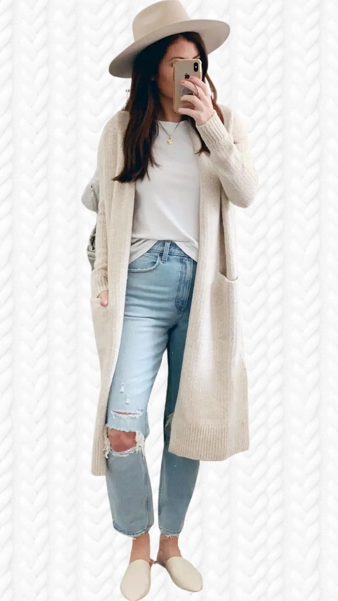 This outfit features a long, beige cardigan made from a soft, textured knit, layered over a white T-shirt. The cardigan has ribbed cuffs, side pockets, and an open front, paired with light blue distressed jeans and cream-colored slip-on mules. A wide-brimmed beige hat completes the look, adding a stylish touch.