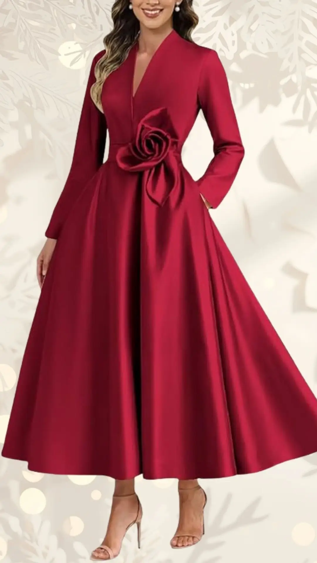 A long sleeve, deep red wedding guest dress features a v-neckline and a prominent rose detail at the waist. The gown flows gracefully to the floor, creating an elegant silhouette, while the model is paired with subtle nude heels. The background is softly adorned, enhancing the overall romantic aesthetic of the outfit.