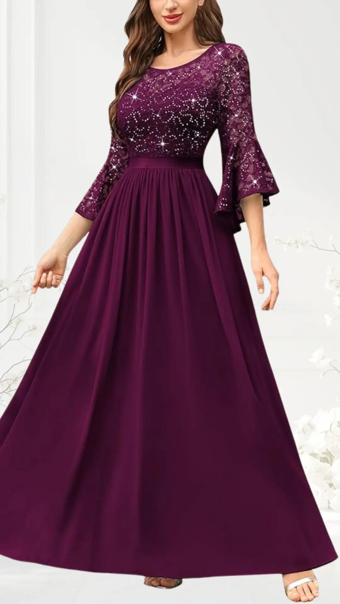 A maroon wedding guest dress features a fitted bodice adorned with sparkling embellishments and elegant sheer three-quarter bell sleeves. The flowing skirt gently cascades to the floor, creating a graceful silhouette perfect for formal occasions.