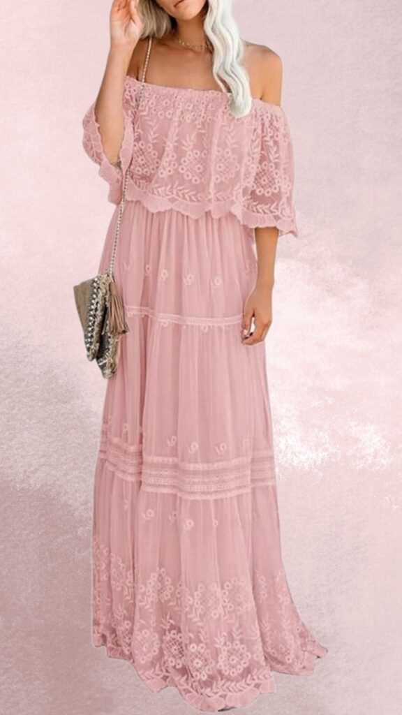 The dress features a soft pink fabric with a flowing maxi length, adorned with delicate floral embroidery and lace trim along the bodice and hem. Off-the-shoulder sleeves add an elegant touch, making it a perfect choice for pairing with cowboy boots for a stylish country western look. An accessory, a small crossbody bag with tassel detailing, complements the outfit seamlessly.
