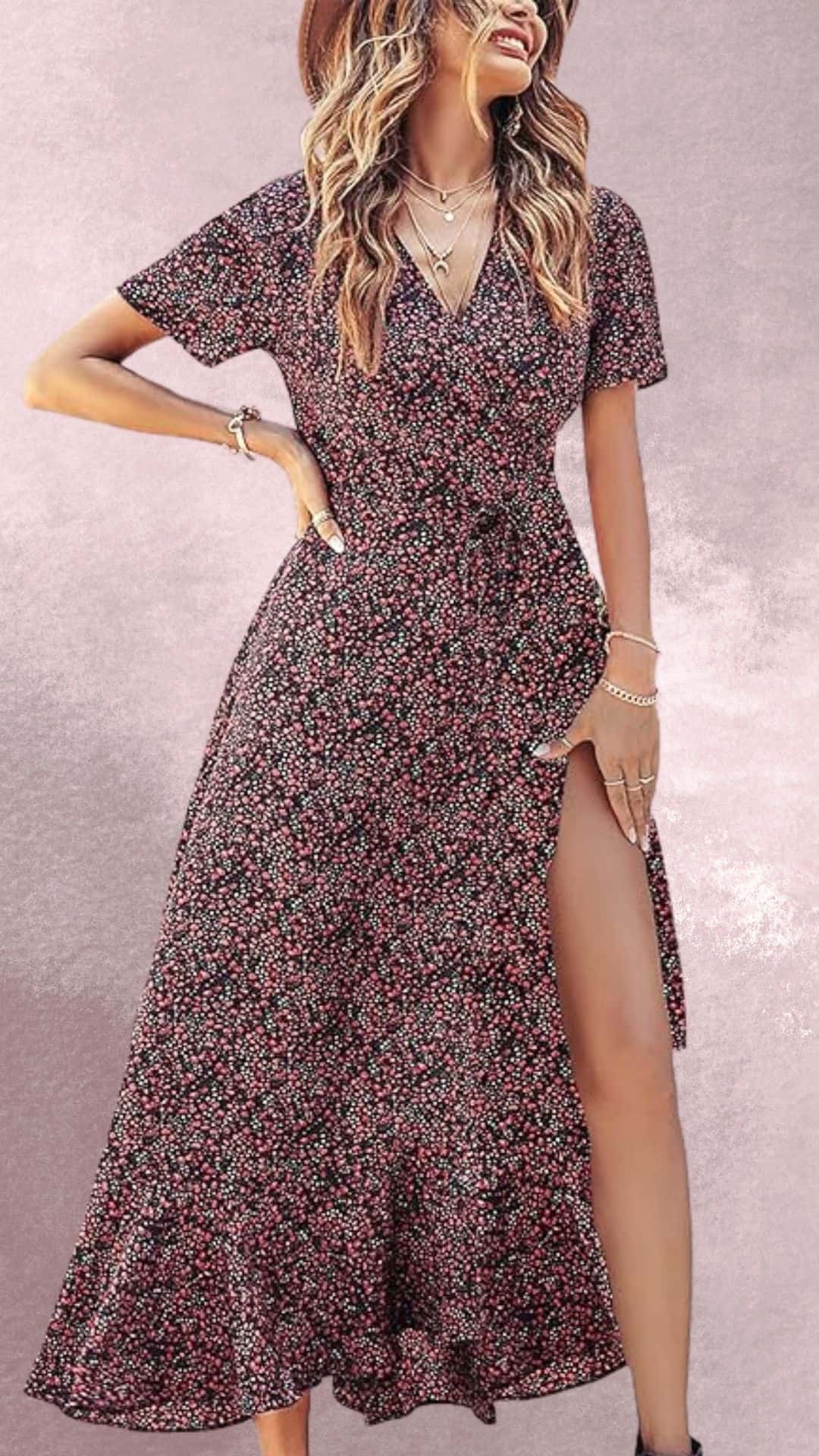 A flowing black maxi dress with short sleeves features a vibrant floral print in shades of pink, white, and green, embodying an elegant country western vibe. The dress has a flattering wrap design and a thigh-high slit that adds a touch of allure, making it perfect to pair with cowboy boots for a stylish look.