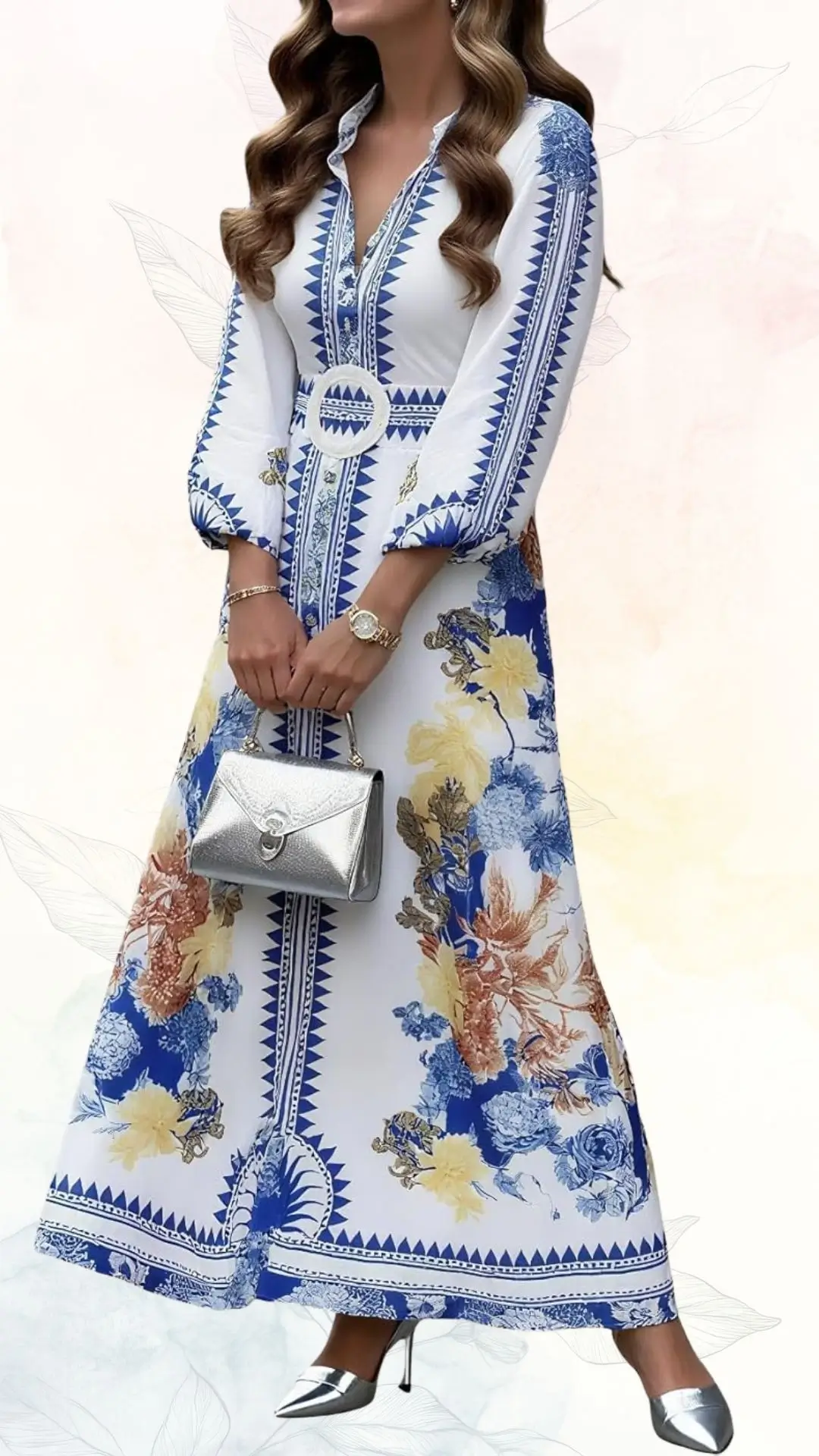 A summer maxi dress features a white base adorned with vibrant blue and golden floral patterns, complemented by a geometric blue trim. It has long sleeves and a fitted bodice, cinched at the waist with a decorative belt, and is paired with silver high-heeled shoes and a small silver handbag. The overall design radiates elegance, perfect for a wedding guest.