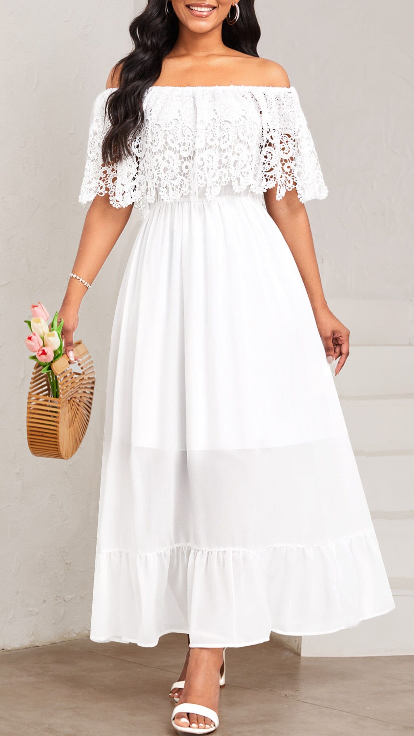 The dress features an off-the-shoulder silhouette with a flared, tiered maxi length, crafted from lightweight chiffon for a soft, flowy look. Its crisp white color and delicate lace overlay at the bodice create a romantic, feminine vibe, making it ideal for a wedding or summer event.