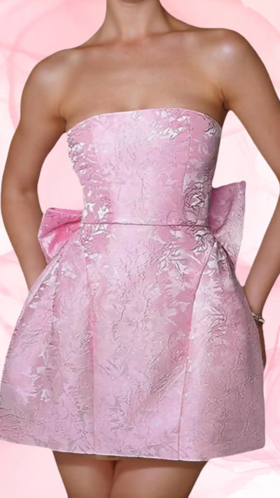 This strapless homecoming dress features a structured, corseted fit with a flared mini skirt, crafted from a textured pastel pink fabric with a delicate floral pattern. The playful design includes oversized side bows, creating a whimsical vibe perfect for a festive occasion like a school dance, appealing to teenage girls seeking a bold yet feminine style.