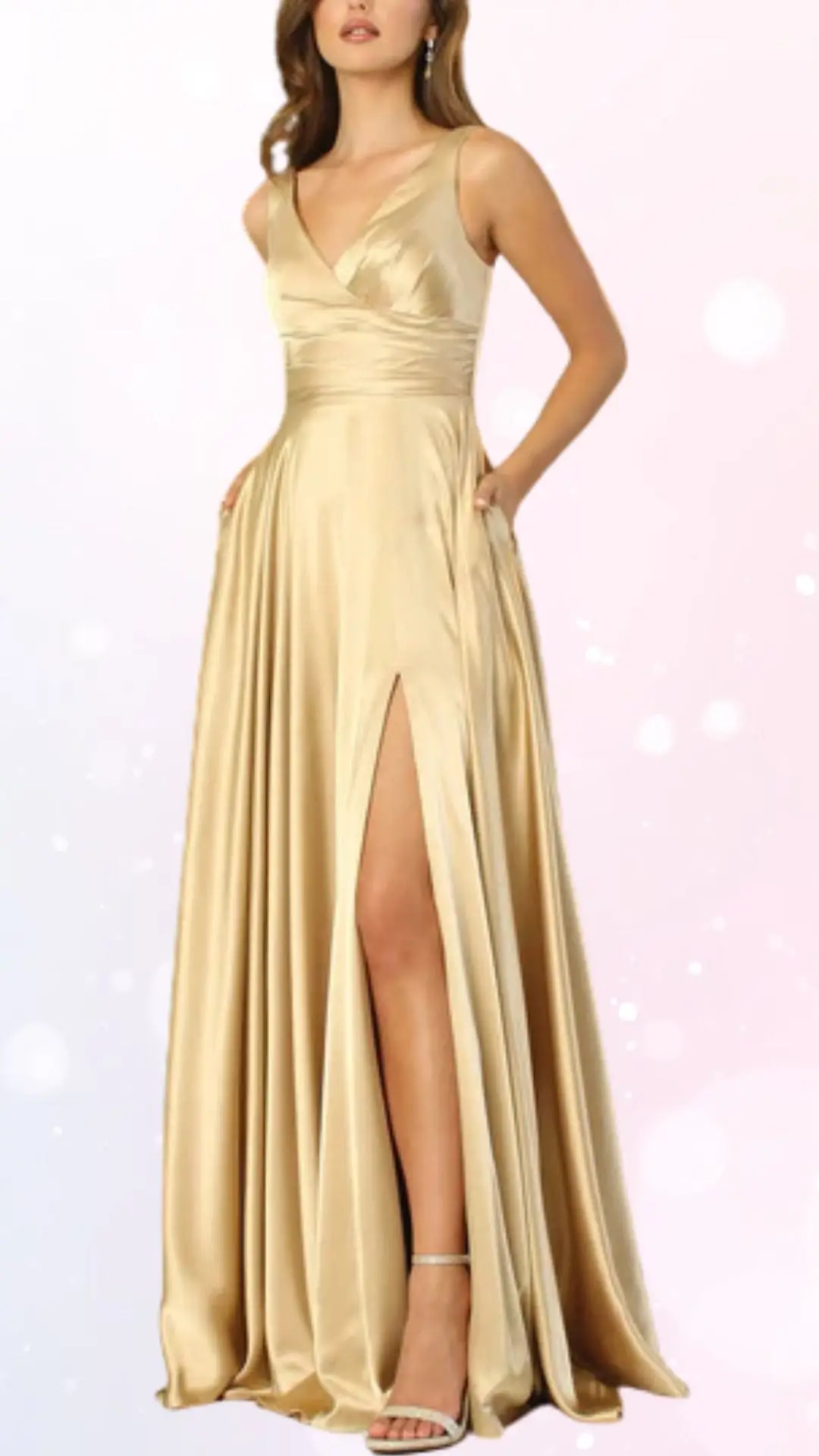 A model wears a flowing, pastel gold wedding guest dress with a deep V-neck and delicate straps. The dress features a high slit on one side, revealing a leg, and is paired with strappy heels, showcasing an elegant and refined look. The background is softly blurred with light pastel colors, enhancing the dress's sophistication.