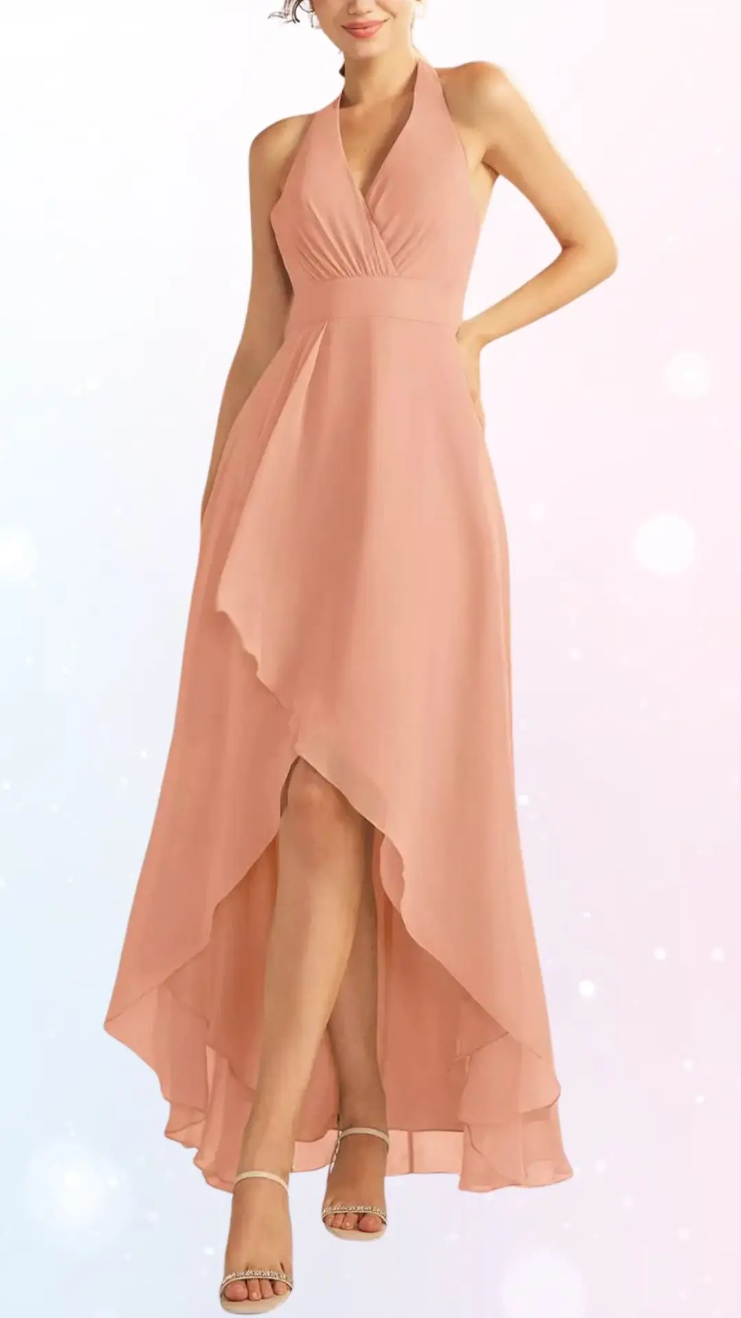 The dress features a halter neckline with a fitted bodice, flowing into a high-low hemline, creating an elegant silhouette. The fabric is a soft pastel peach, ideal for spring weddings, and the model pairs it with delicate, strappy sandals. The overall look is graceful and chic, emphasizing movement and lightness.
