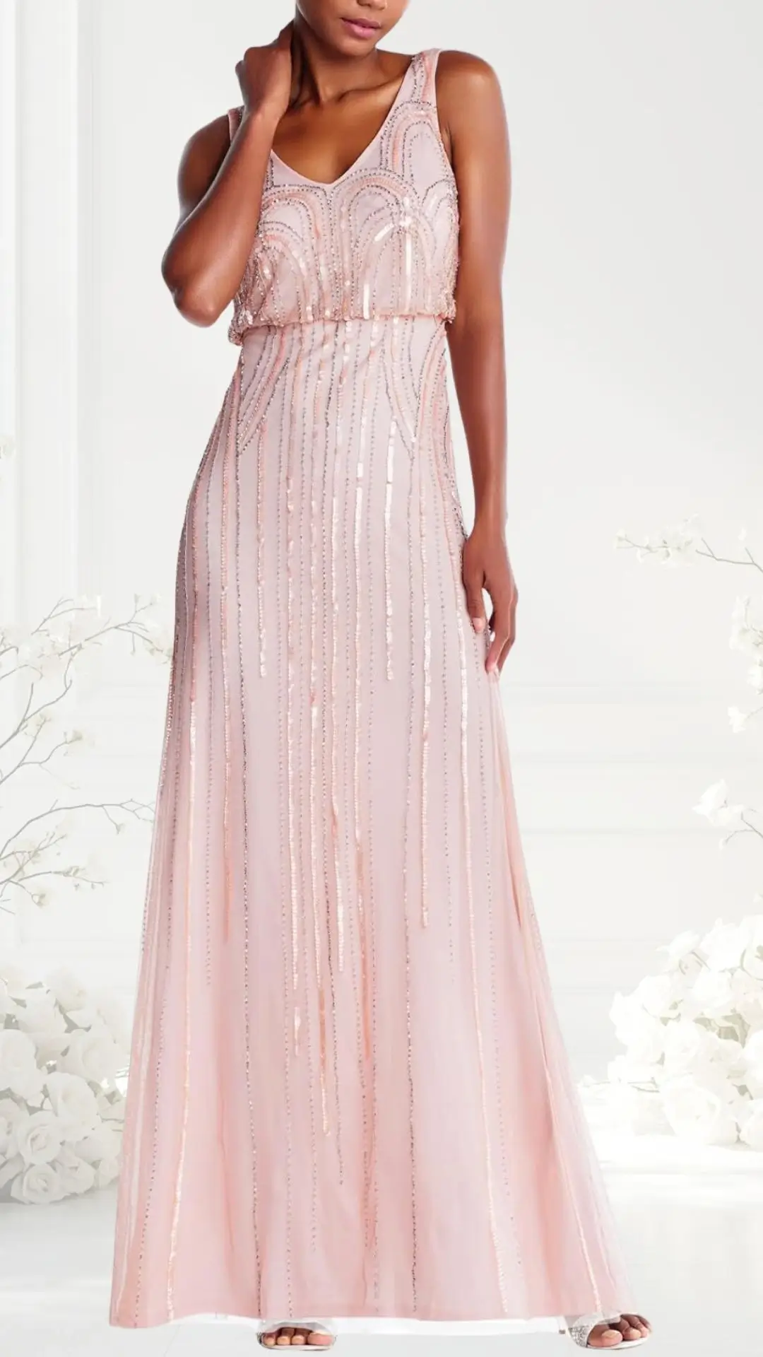 A blush pink wedding guest dress features a fitted bodice adorned with intricate beading and sequins that create a shimmering effect. The floor-length skirt flows gently, accentuating a graceful silhouette, while delicate straps highlight the shoulders. The overall design exudes elegance, perfect for formal occasions.