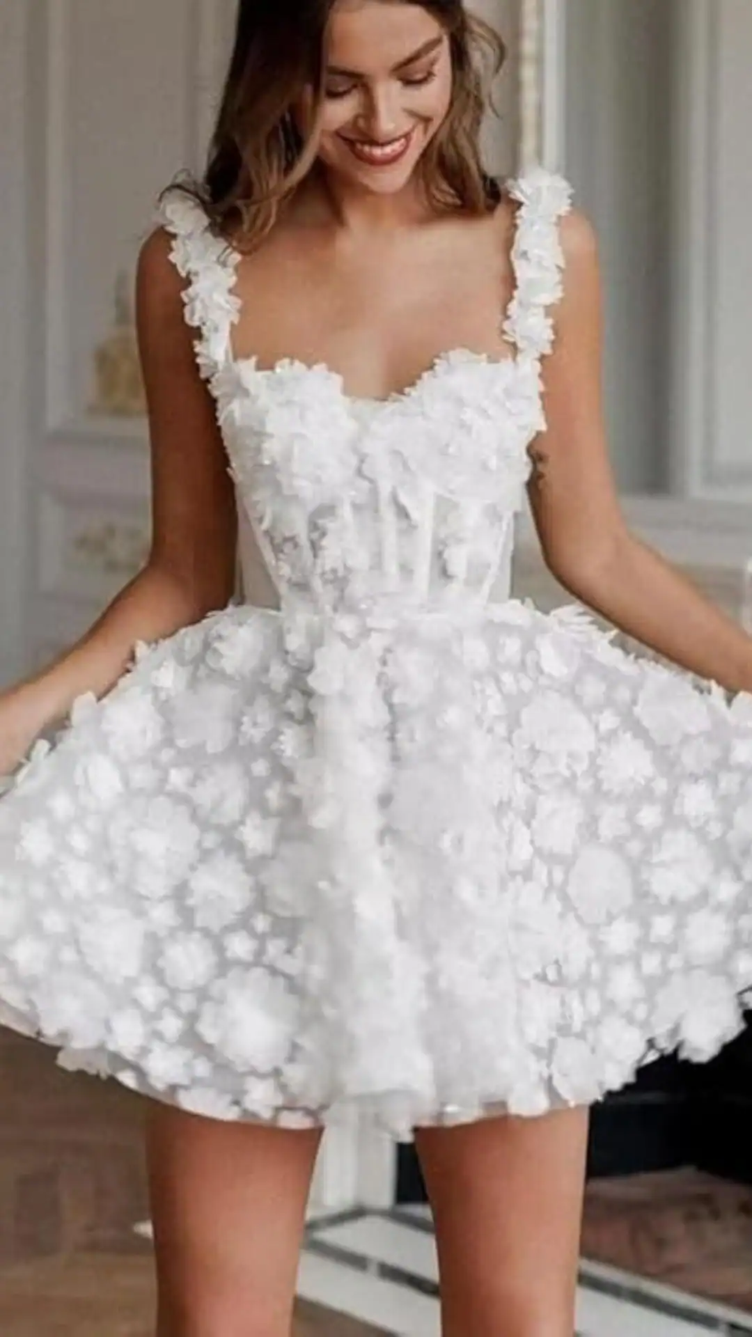 This homecoming dress showcases a playful, flared silhouette with a fitted bodice enhanced by floral appliqués, creating a romantic and ethereal vibe. Crafted from a soft fabric, layered with textured floral designs in a pure white hue, it is perfect for a formal event or school dance, making it an ideal choice for teenage girls seeking a fresh and trendy look.