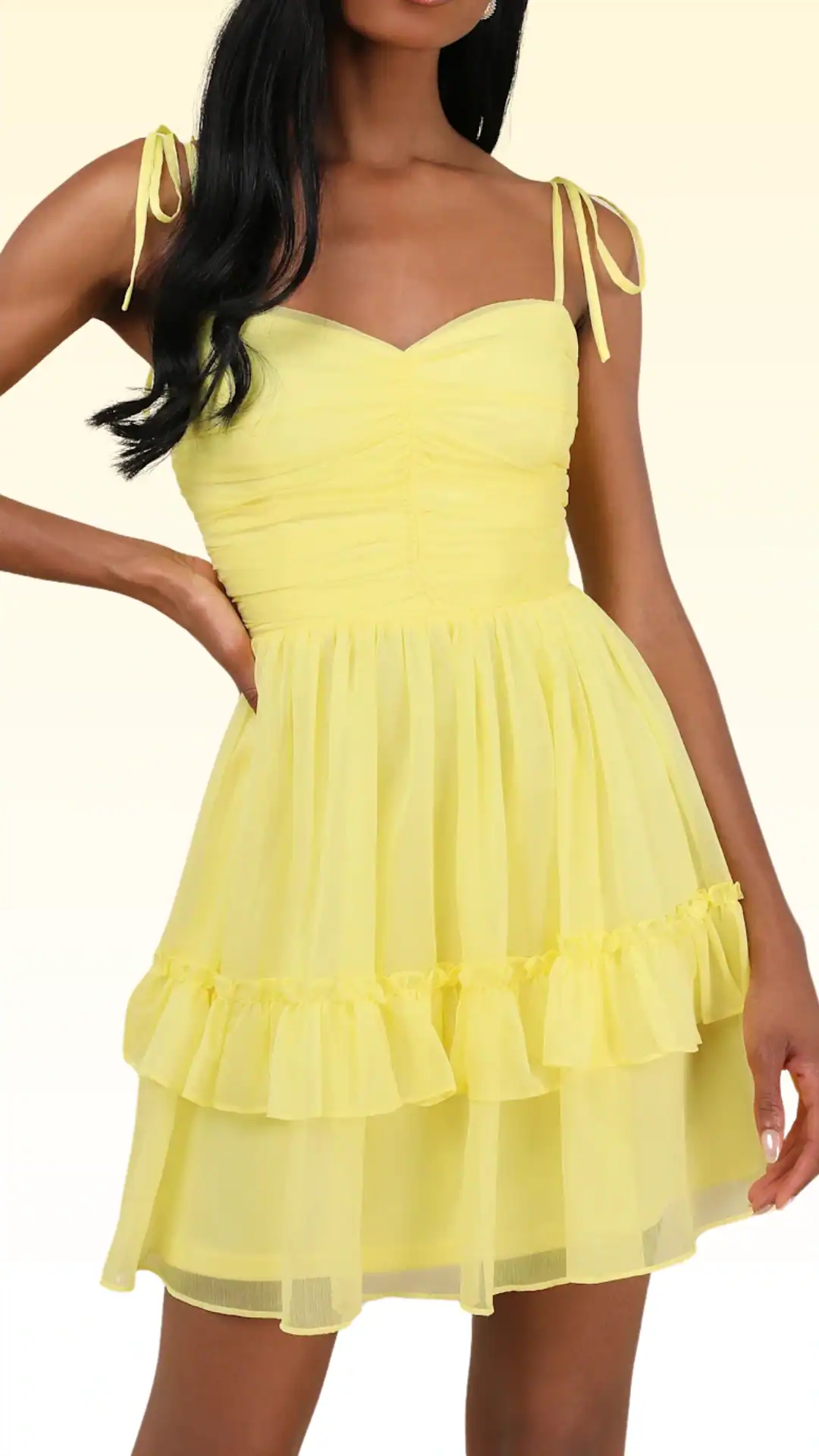 This playful yellow homecoming dress features a fitted bodice with delicate tie straps, a ruched texture, and a flouncy layered skirt that creates a fun, flirty vibe. Crafted from lightweight, sheer fabric, the dress exudes a cheerful and youthful aesthetic, making it perfect for teenage girls celebrating homecoming or other festive occasions.