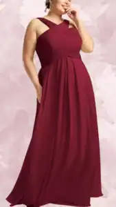 A plus-size wedding guest dress in a rich burgundy color features a fitted bodice with crisscross straps that create an elegant off-the-shoulder look. The empire waist flows into a sweeping, floor-length skirt, enhancing the silhouette, while hidden pockets add practicality. The dress showcases soft, ruched detailing, providing texture and visual interest throughout.