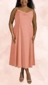The dress is a plus-size wedding guest option featuring a soft cowl neckline and adjustable spaghetti straps. It's crafted from a flowing fabric that skims the body, with a midi-length A-line silhouette that starts at the waist and gently flares out towards the hem. The dress is in a light peach color, offering a fresh and romantic look perfect for a wedding setting.