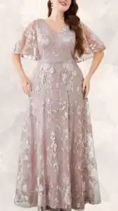 This plus size wedding guest dress features a soft dusty rose fabric adorned with intricate floral embroidery in shades of white, creating a delicate and romantic look. It has a flattering V-neckline and elegant knee-length flutter sleeves, complemented by a flowing, floor-length skirt with a subtle, sheer overlay. The combination of the elegant floral pattern and soft color adds a sophisticated charm, perfect for any wedding celebration.