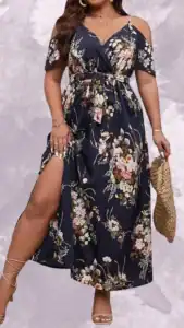This plus-size wedding guest dress features a wrap-style design with cold-shoulder flutter sleeves and a deep V-neckline, cinched at the waist with a matching tie. The floor-length skirt has a high slit for added elegance, adorned with a vibrant floral pattern in soft pinks, whites, and greens against a rich navy background. The overall look combines comfort and sophistication, making it an ideal choice for festive occasions.