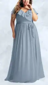 A flowing plus-size wedding guest dress in a soft blue tone features a v-neckline with delicate ruffle detailing along the bust and flutter sleeves. The waist is cinched with a fabric belt, leading to a generously pleated maxi length that creates an elegant silhouette. The overall design balances comfort and style, making it a perfect choice for various wedding settings.