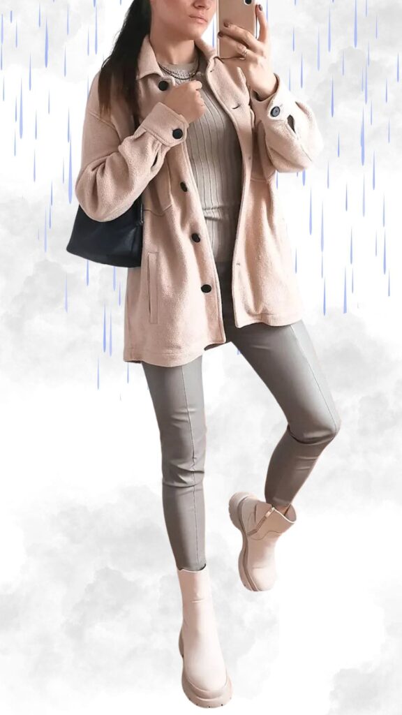 The outfit features a soft, pale pink fleece coat with black buttons, providing warmth and a chic look. Underneath, a light gray ribbed sweater complements the fitted, light gray faux leather leggings that enhance the silhouette. The ensemble is completed with stylish, waterproof ankle boots in a coordinating soft blush tone, ideal for staying dry and fashionable in rainy autumn and winter weather.