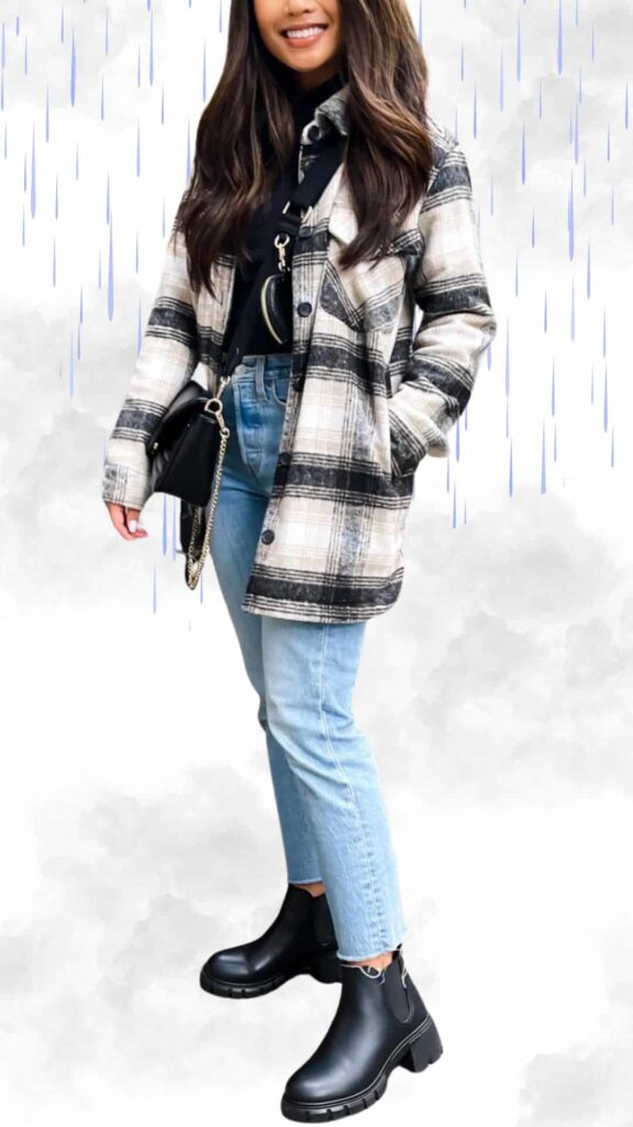 A stylish rainy day outfit features a black and white plaid shacket layered over a fitted black turtleneck, providing warmth and texture. Paired with light blue cropped jeans and sleek black ankle rain boots, the ensemble is both chic and functional. Minimal accessories include a small black crossbody bag, perfect for a polished look in wet weather.