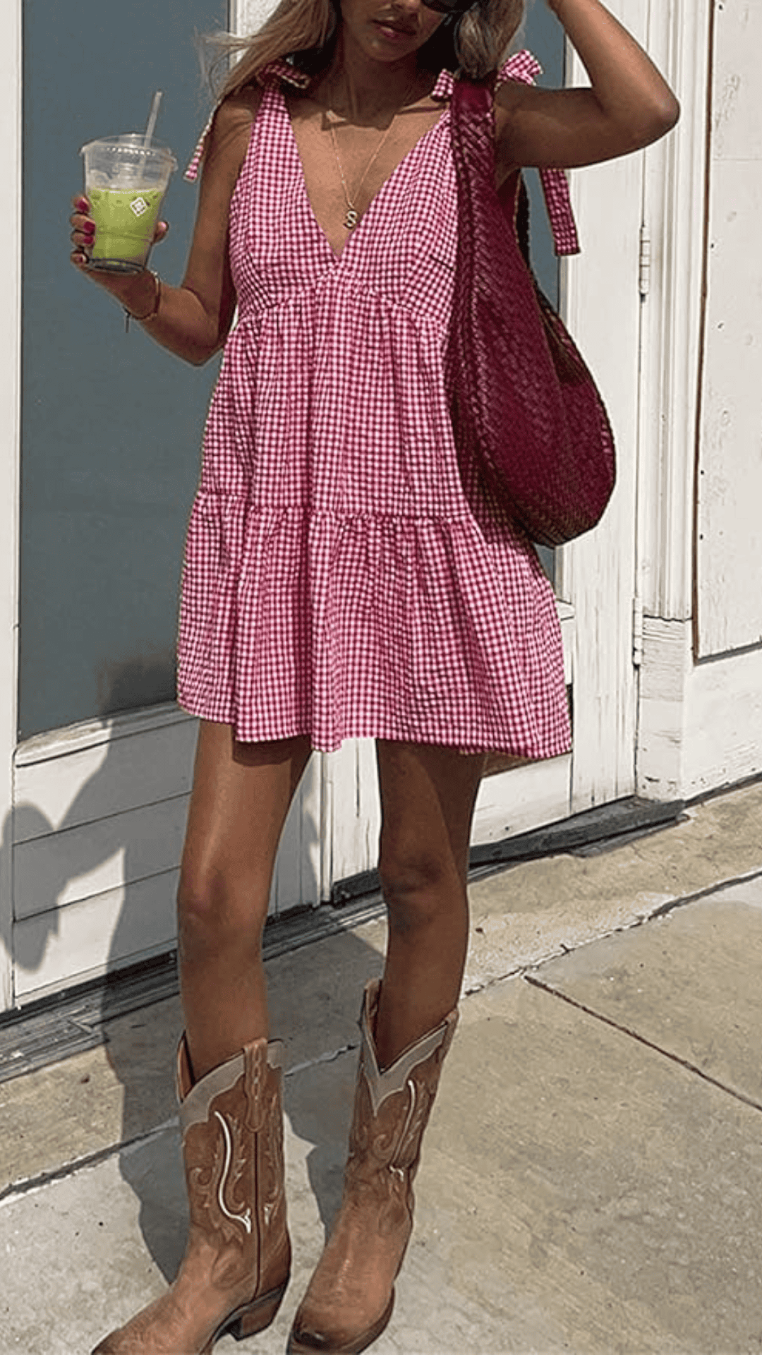 This red and white gingham dress features a playful, tiered design with a deep V-neck and flowy silhouette, perfect for casual summer outings. Made from lightweight cotton, it exudes a relaxed, festive vibe complemented by cowboy boots, making it an ideal choice for 4th of July celebrations.