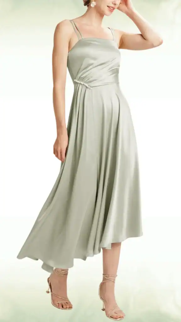 This sage green dress features a flowing, satin fabric that offers a sleek and elegant texture, perfect for a formal occasion. With slender straps and a fitted bodice that flares into a slightly voluminous skirt, it exudes a romantic vibe suitable for a fall wedding, making it an ideal choice for teenage guests.