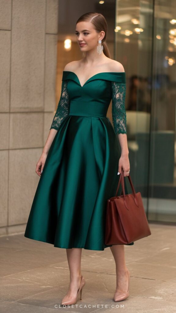 A woman walks confidently in a deep emerald green, off-the-shoulder dress featuring elegant lace long sleeves and a flared skirt. She carries a rich brown handbag and wears pale pink high heels, accentuating the sophisticated, semi-formal look. Sparkling earrings complete the outfit, adding a touch of glamour.