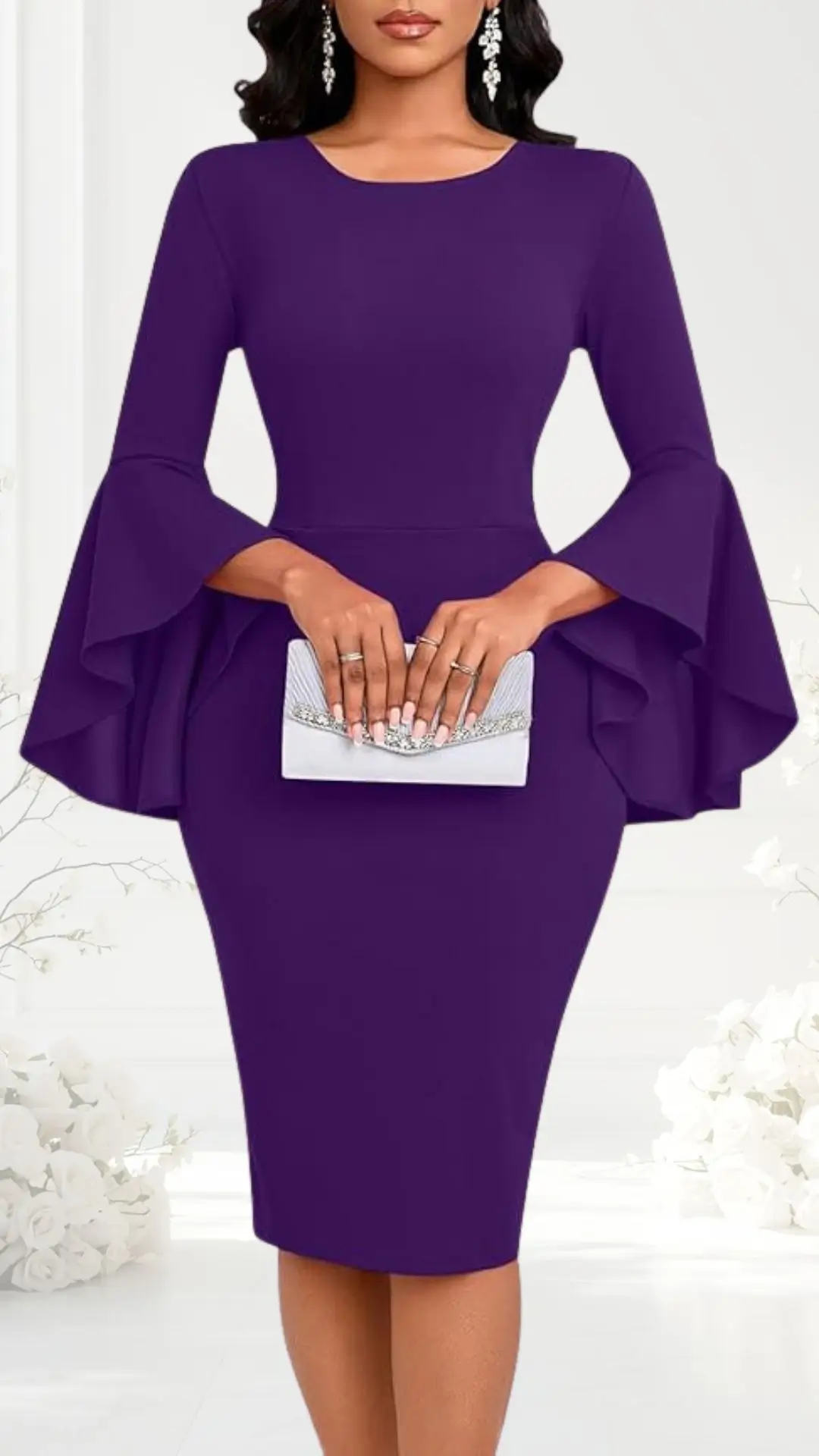 A fitted, knee-length dress in a rich purple hue features long, flared sleeves that add a touch of elegance. The model is holding a silver, embellished clutch, enhancing the sophisticated look suitable for a semi-formal wedding. The background includes soft, white floral elements, creating a romantic atmosphere.