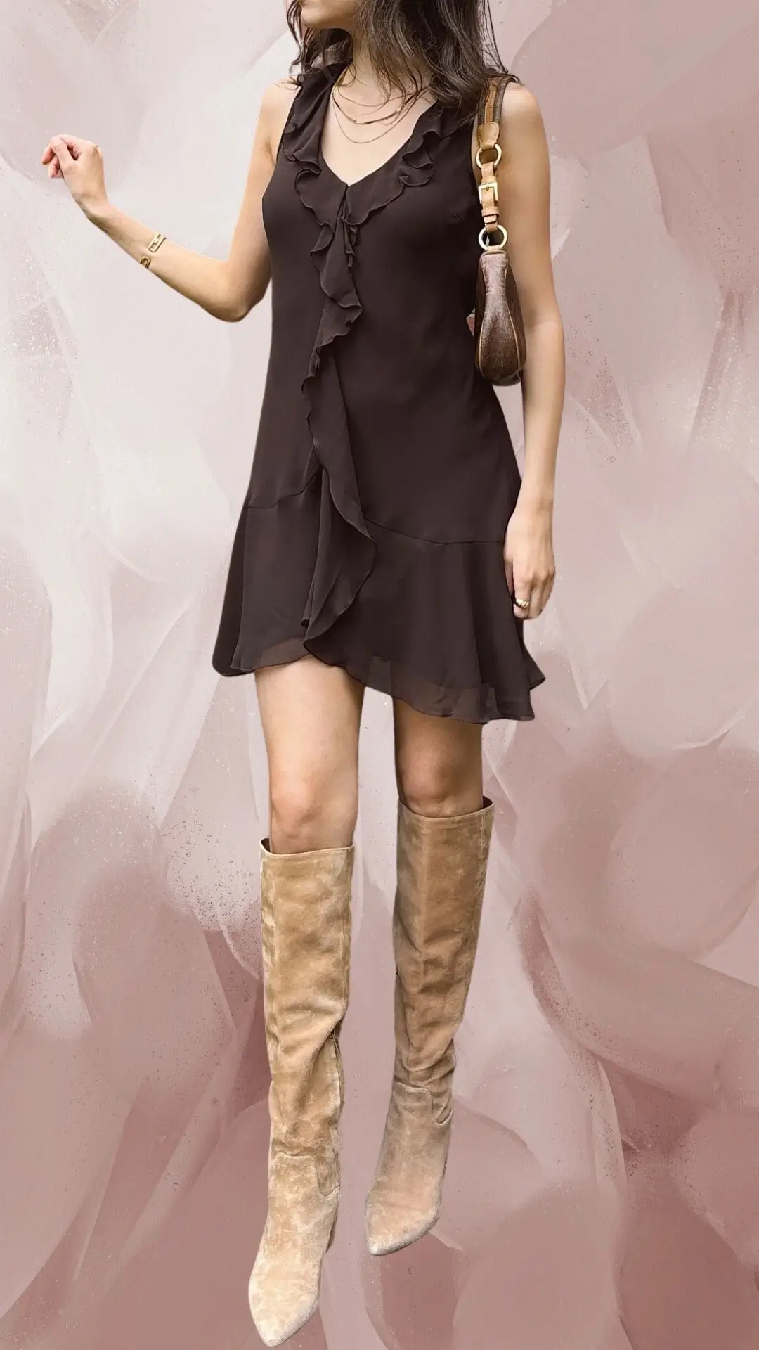 The outfit features a short brown dress made from lightweight fabric with a flowy silhouette, adorned with delicate ruffles along the neckline and front. It is complemented by knee-high, beige suede boots that enhance the chic and stylish appearance. The overall look balances sophistication with a relaxed vibe, ideal for various occasions.