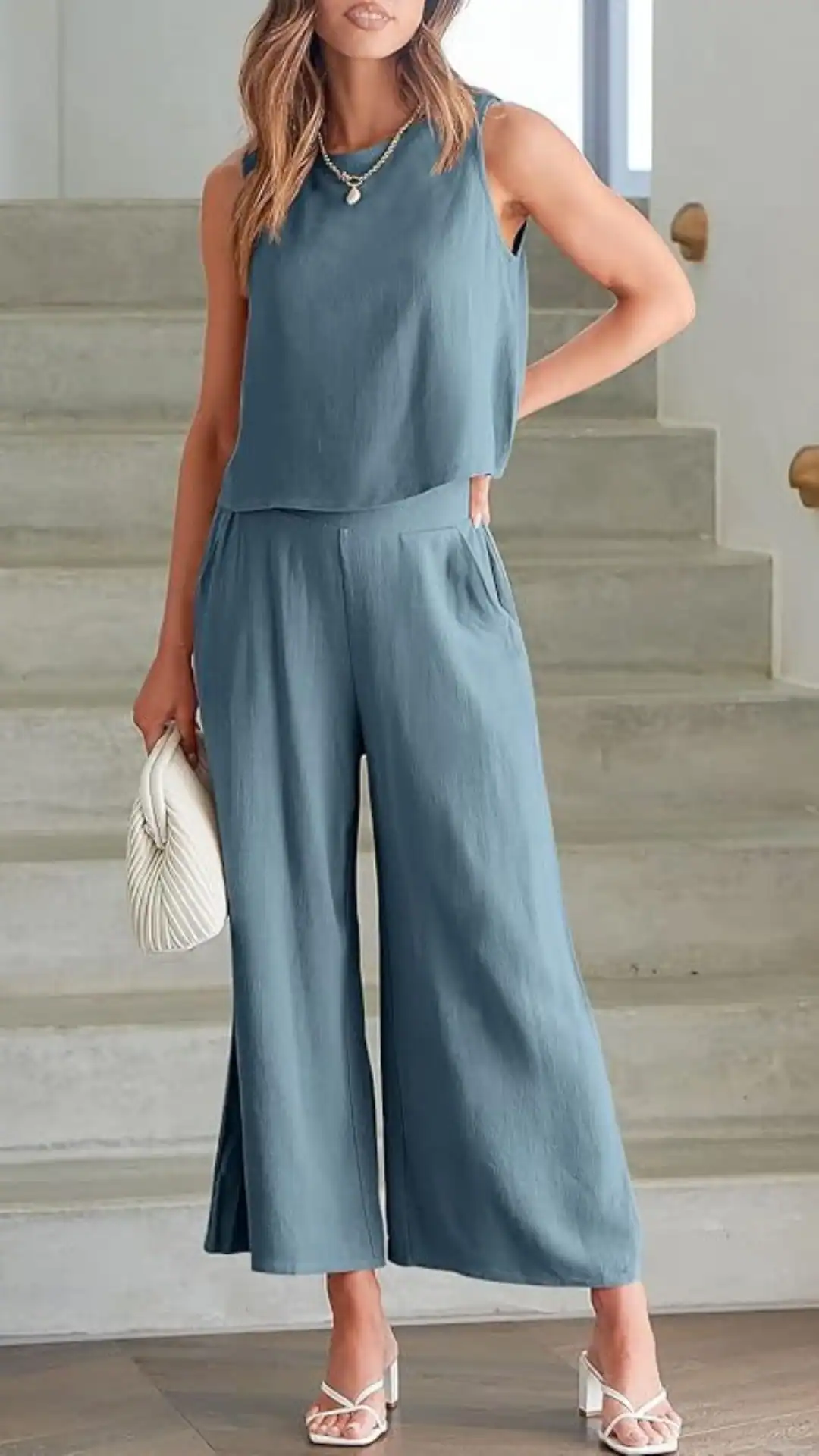 A matching linen set featuring a sleeveless, slightly cropped top and wide-leg pants in a soft slate blue hue, offering a lightweight, breathable texture. This casual yet polished outfit radiates a relaxed, modern vibe, ideal for summer outings or brunch gatherings.