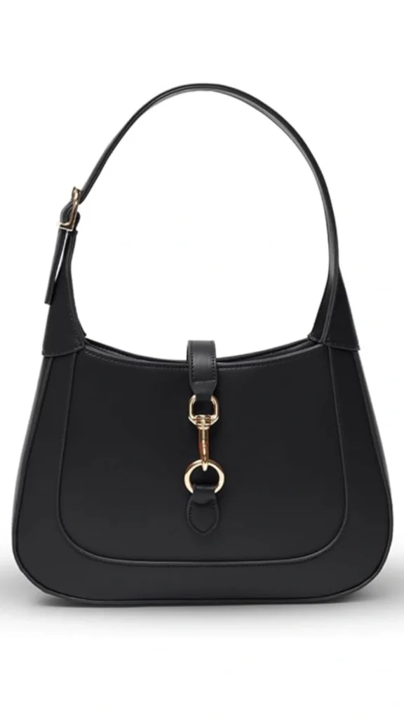 This image features a sleek black amazon handbag with a minimalist design, characterized by smooth, structured leather and a distinctive gold-tone clasp detail at the front. The bag has a single, rounded shoulder strap, providing a comfortable carry option while maintaining an elegant silhouette. Its versatile color and understated design make it an excellent accessory for casual everyday outfits.