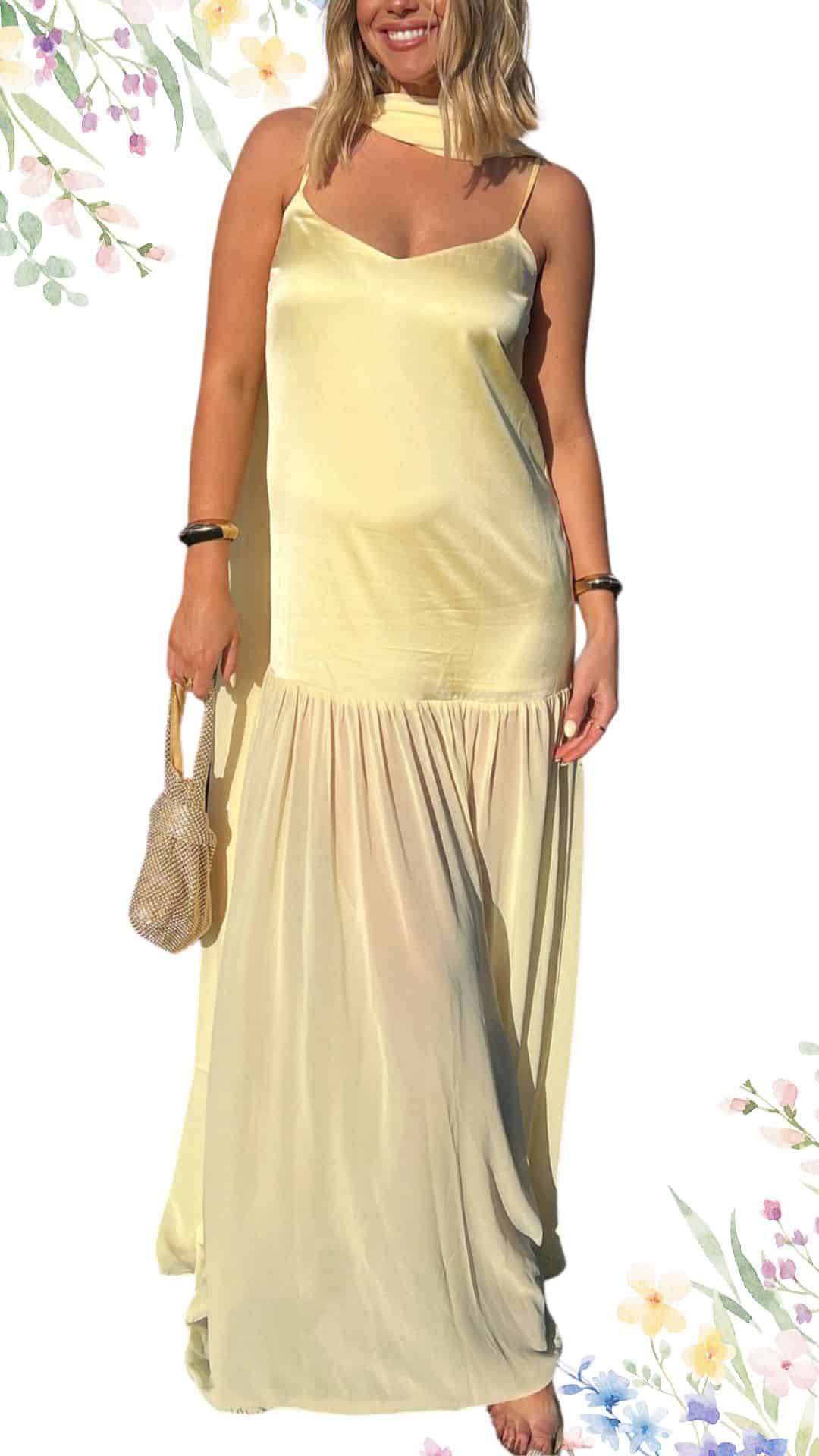 This elegant spring wedding guest dress features a flowing design in a soft, pastel yellow hue, exuding a fresh and sophisticated vibe. The gown has a V-neckline, slender spaghetti straps, and a tiered silhouette that flows gracefully to the floor, while a delicate, matching scarf adds a touch of refinement. The silky texture enhances its luxurious appearance, making it ideal for a formal occasion.