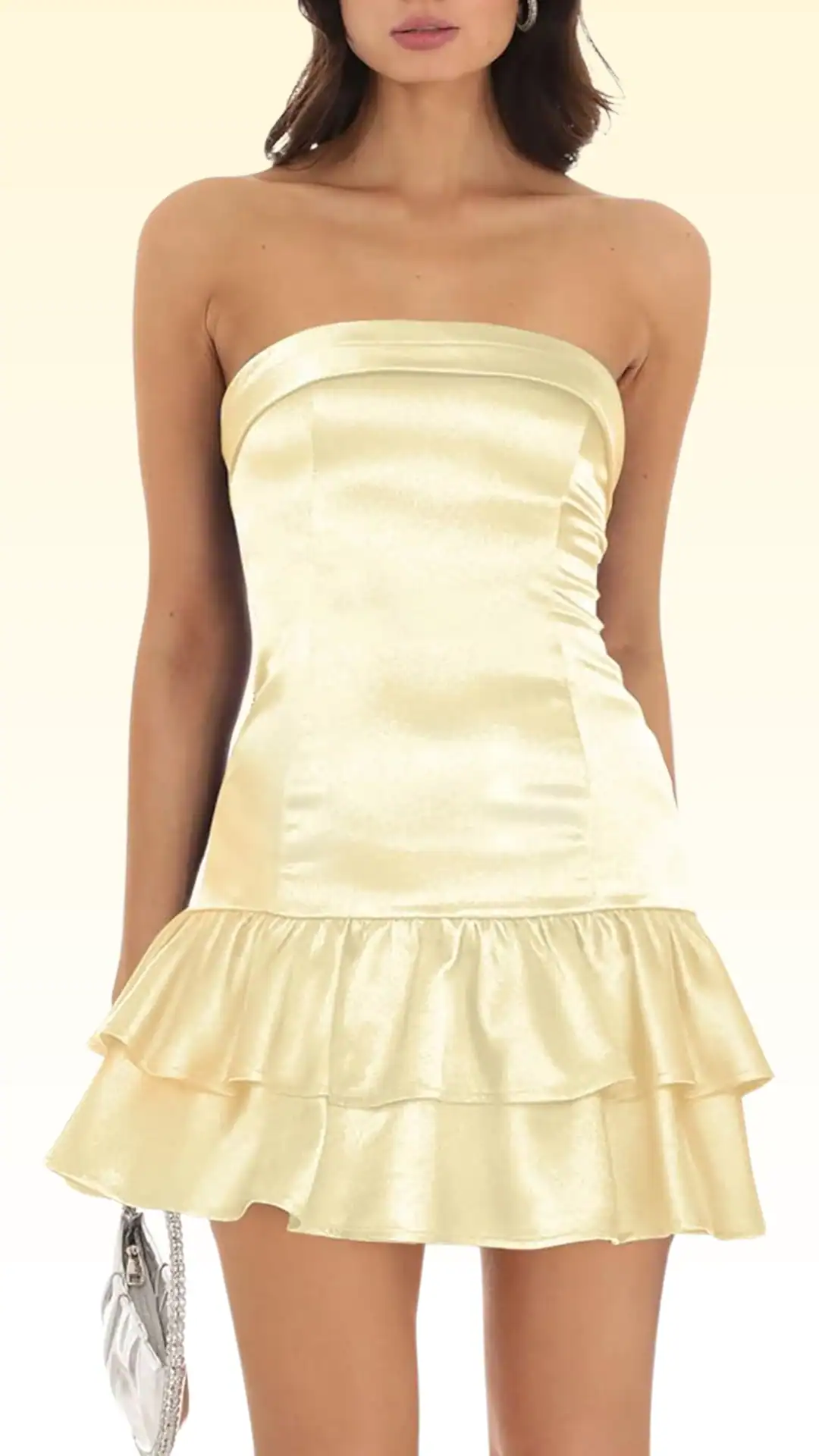 This strapless homecoming dress is crafted from a silky, smooth fabric in a soft pastel yellow hue, featuring a fitted bodice that flares into a playful, tiered ruffle skirt, embodying a cute and youthful vibe. Perfect for formal occasions like homecoming or school dances, it offers a flattering fit that accentuates the waist while providing volume through its layered design.