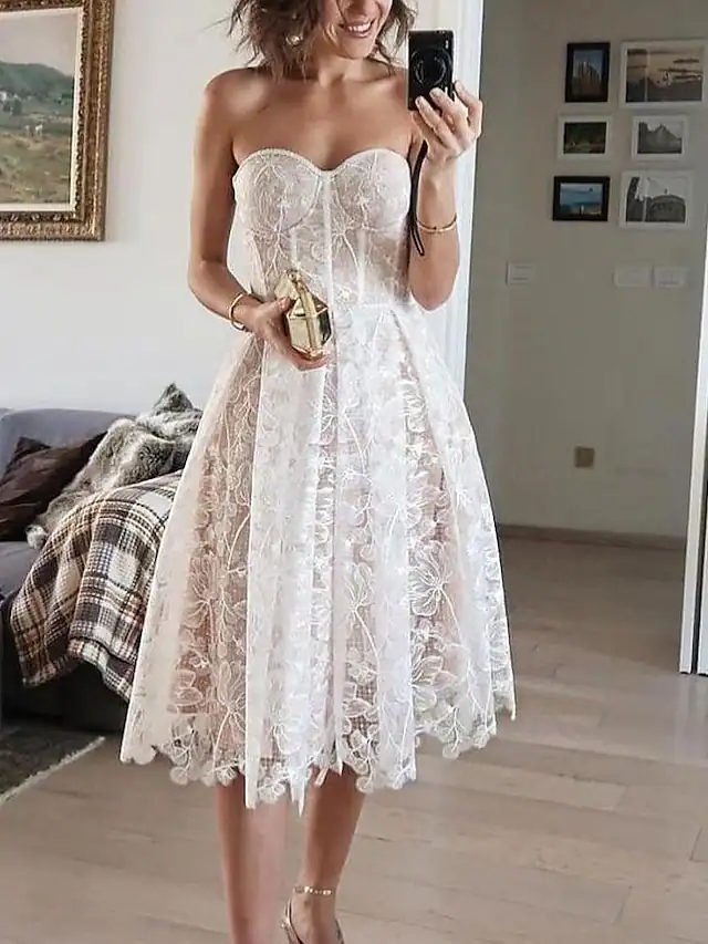 Woman wearing a strapless white lace midi dress with a fitted bodice and scalloped hem, perfect for summer events or bridal occasions
