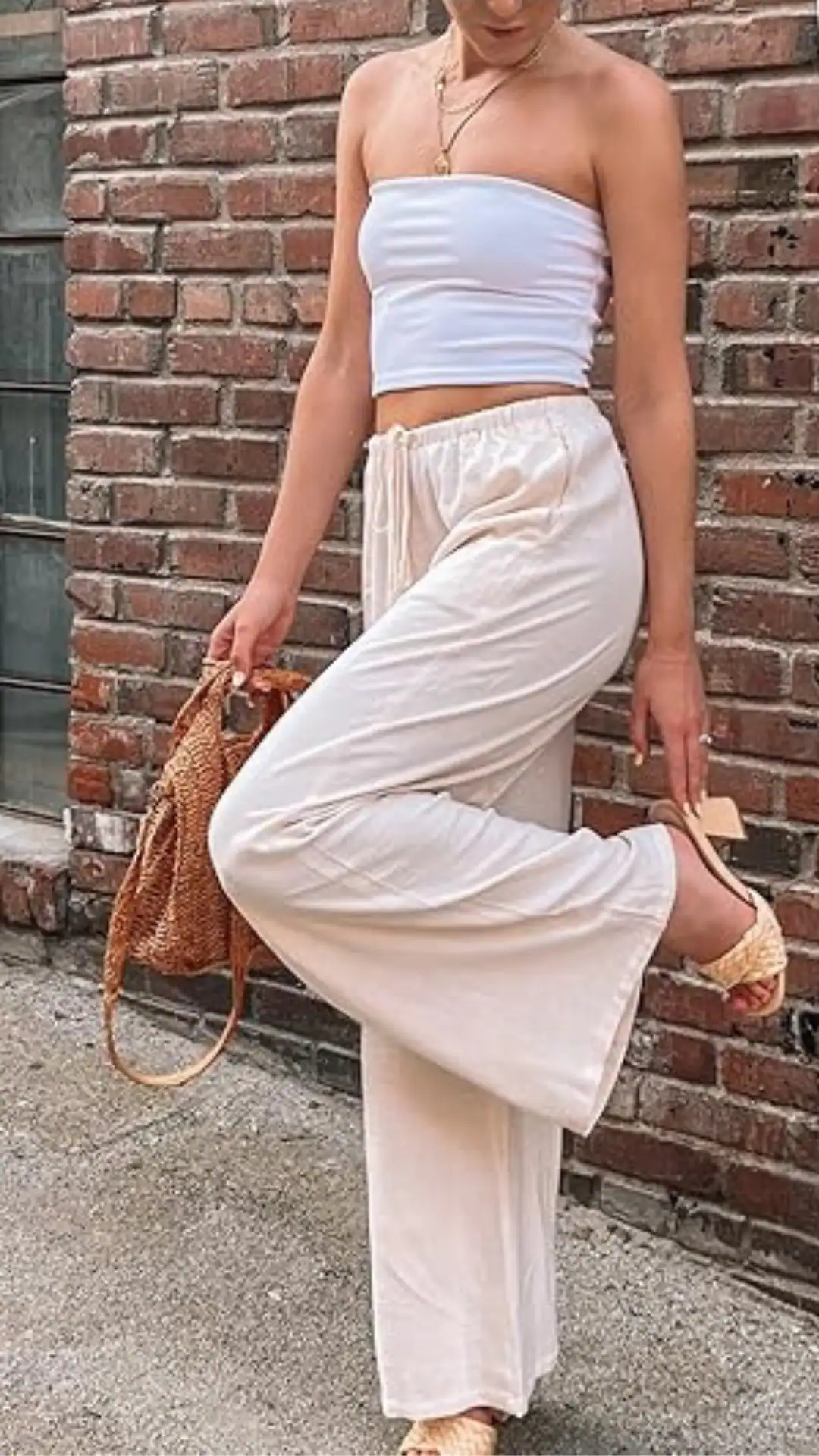 This outfit features a lightweight cream linen pant and a fitted white strapless top, creating a relaxed yet stylish look with a soft texture perfect for summer. The overall vibe is casual and effortless, ideal for a daytime outing or beach event.