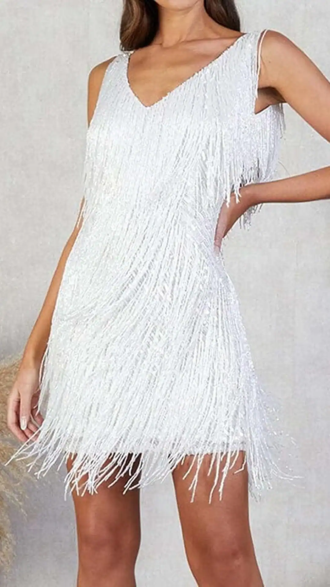 This white homecoming dress features a chic A-line silhouette with a V-neckline and a flapper-inspired design, adorned with shimmering fringe that adds a playful texture. Ideal for a lively party atmosphere, the dress offers a fitted style that flatters the figure, creating a fun and trendy vibe for teenage girls at special events.