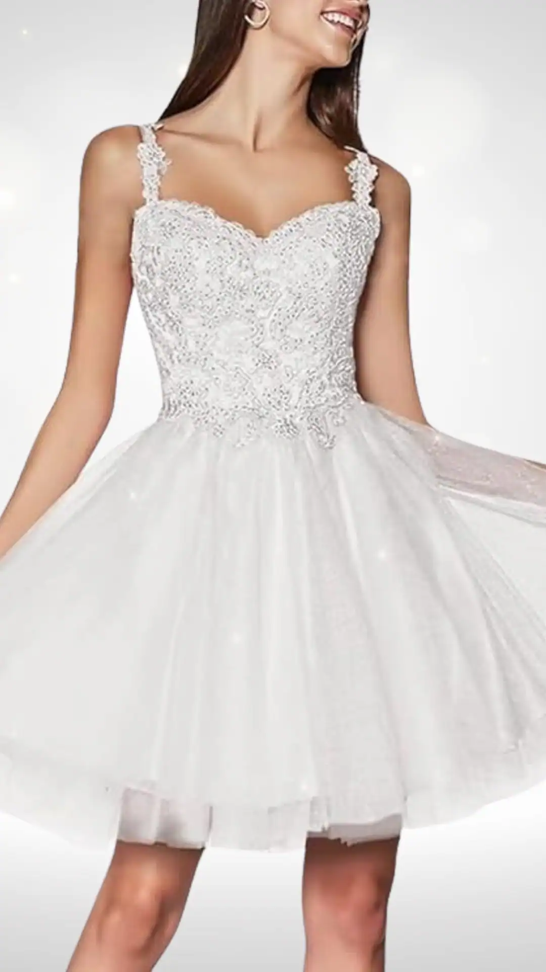 This white homecoming dress features a fitted, embellished bodice adorned with delicate beading, complemented by adjustable spaghetti straps for a customizable fit. The ethereal, voluminous skirt flares out from the waist, creating a romantic and playful silhouette ideal for formal events like homecoming or school dances.